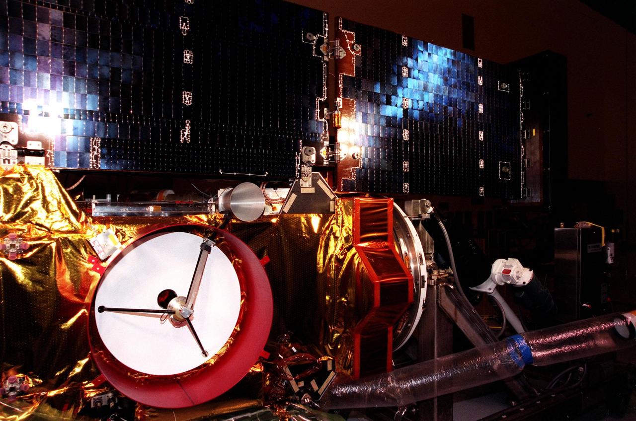 Bright white light (left) and blue light (upper right) appear on the solar panels of the <a href="http://www-pao.ksc.nasa.gov/kscpao/captions/subjects/stardust.htm"> Stardust</a> spacecraft during lighting tests in the Payload Hazardous Servicing Facility. Stardust is scheduled to be launched aboard a Boeing Delta II rocket from Launch Pad 17A, Cape Canaveral Air Station, on Feb. 6, 1999, for a rendezvous with the comet Wild 2 in January 2004. Stardust will use a substance called aerogel to capture comet particles flying off the nucleus of the comet, plus collect interstellar dust for later analysis. The collected samples will return to Earth in a sample return capsule to be jettisoned as it swings by Earth in January 2006