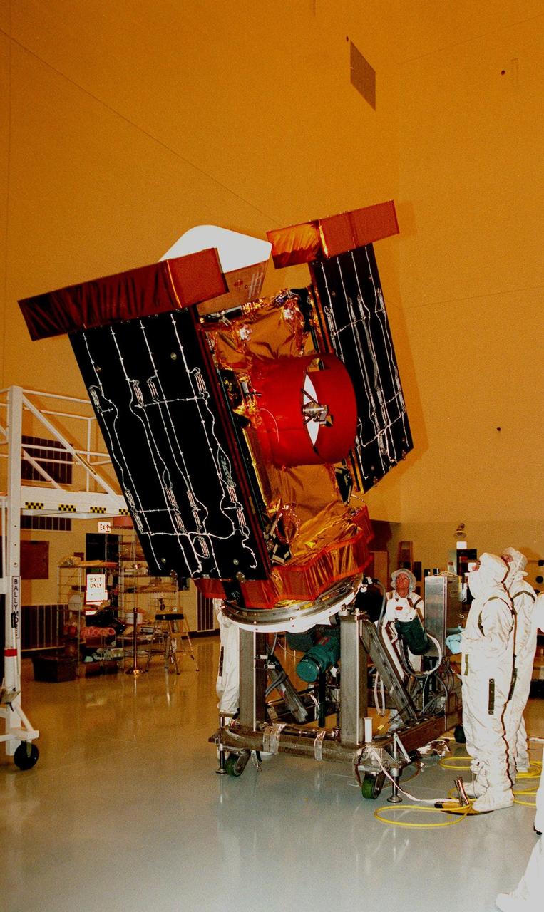 In the Payload Hazardous Servicing Facility, workers get ready to rotate the <a href="http://www-pao.ksc.nasa.gov/kscpao/captions/subjects/stardust.htm"> Stardust</a> spacecraft before deploying the solar panels (at left and right) for lighting tests. Stardust is scheduled to be launched aboard a Boeing Delta II rocket from Launch Pad 17A, Cape Canaveral Air Station, on Feb. 6, 1999, for a rendezvous with the comet Wild 2 in January 2004. Stardust will use a substance called aerogel to capture comet particles flying off the nucleus of the comet, plus collect interstellar dust for later analysis. The collected samples will return to Earth in a sample return capsule to be jettisoned as it swings by Earth in January 2006