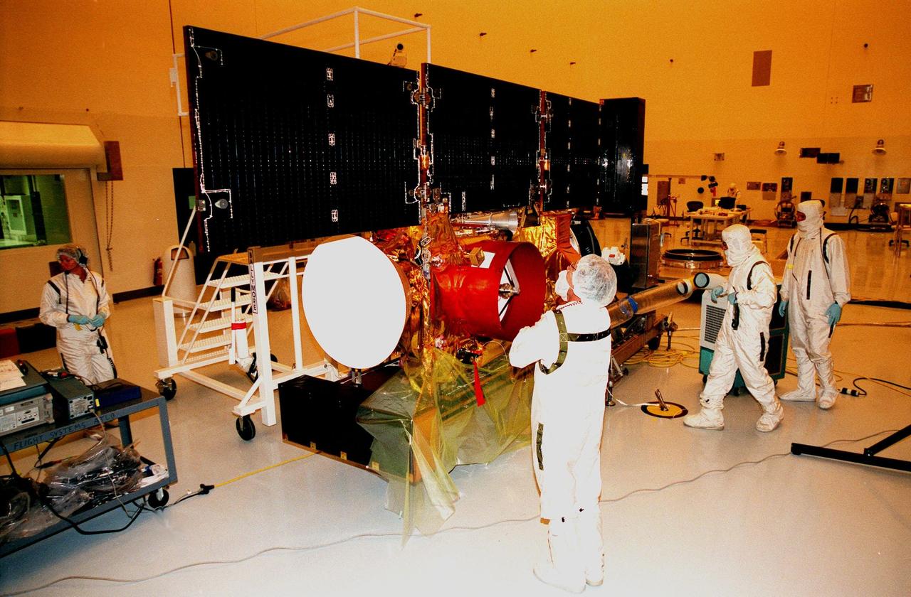 In the Payload Hazardous Servicing Facility, workers look over the solar panels on the <a href="http://www-pao.ksc.nasa.gov/kscpao/captions/subjects/stardust.htm"> Stardust</a> spacecraft that are deployed for lighting tests. Stardust is scheduled to be launched aboard a Boeing Delta II rocket from Launch Pad 17A, Cape Canaveral Air Station, on Feb. 6, 1999, for a rendezvous with the comet Wild 2 in January 2004. Stardust will use a substance called aerogel to capture comet particles flying off the nucleus of the comet, plus collect interstellar dust for later analysis. The collected samples will return to Earth in a sample return capsule to be jettisoned as it swings by Earth in January 2006