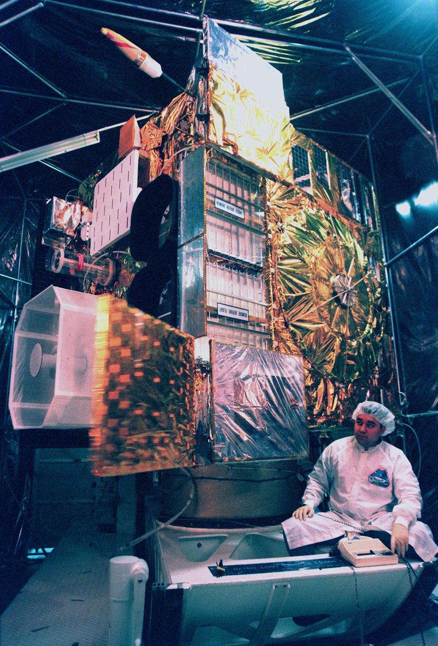 With the light casting a rosy glow in a specially built clean room at Astrotech, Titusville, Fla., Loral technician Roberto Caballero tests the deployment of the sounder instrument's cooler cover door on the <a href="http://www-pao.ksc.nasa.gov/kscpao/captions/subjects/goes-l.htm">GOES-L</a> weather satellite. The sounder, one of two meteorological instruments on the satellite, measures temperature and moisture in a vertical column of air from the satellite to Earth. Its findings will help forecast weather. GOES-L, which is to be launched from Cape Canaveral Air Station aboard an Atlas II rocket in late March, is the fourth of a new advanced series of geostationary weather satellites for the National Oceanic and Atmospheric Administration. It is a three-axis inertially stabilized spacecraft that will provide pictures as well as perform the atmospheric sounding. Once launched, the satellite, to be designated GOES-11, will undergo checkout and provide backup capabilities for the existing, aging GOES East weather satellite