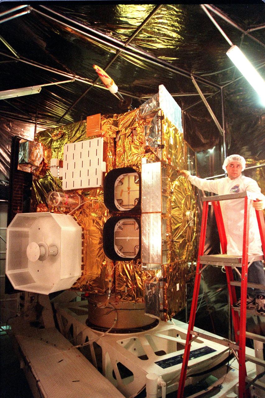 In a specially built clean room at Astrotech, Titusville, Fla., Loral technician Roberto Caballero checks the position of the <a href="http://www-pao.ksc.nasa.gov/kscpao/captions/subjects/goes-l.htm">GOES-L</a> weather satellite before beginning deployment of the sounder instrument's cooler cover door. The sounder, one of two meteorological instruments on the satellite, measures temperature and moisture in a vertical column of air from the satellite to Earth. Its findings will help forecast weather. GOES-L, which is to be launched from Cape Canaveral Air Station aboard an Atlas II rocket in late March, is the fourth of a new advanced series of geostationary weather satellites for the National Oceanic and Atmospheric Administration. It is a three-axis inertially stabilized spacecraft that will provide pictures as well as perform the atmospheric sounding. Once launched, the satellite, to be designated GOES-11, will undergo checkout and provide backup capabilities for the existing, aging GOES East weather satellite