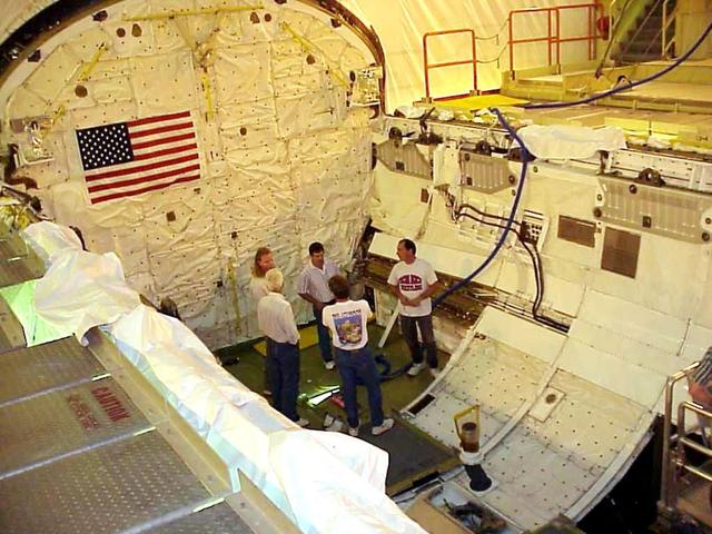 KENNEDY SPACE CENTER, FLA. -- KSC workers stand inside the payload bay of the orbiter Columbia following completion of electrical wiring inspections. At right, behind and below them is the cable tray with the wiring. During launch of Columbia on mission STS-93, a damaged wire caused a short circuit in two separate main engine controllers. As a result of the findings, Shuttle program managers decided to conduct inspections of the wiring in Endeavour's payload bay before its next mission, STS-99. The inspection and possible repair work will lead to a delayed launch date no earlier than Oct.7. The primary payload of the mission is the Shuttle Radar Topography Mission, a specially modified radar system that will gather data for the most accurate and complete topographic map of the Earth's surface that has ever been assembled