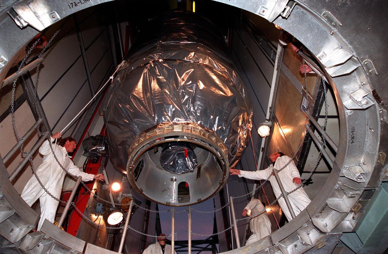 Workers inside the launch tower at Pad 17-A, Cape Canaveral Air Station, guide the third stage of a Boeing Delta II rocket, and the Stardust spacecraft connected to it, through an opening to the second stage of the rocket below. The second and third stages of teh rocket will be mated next as preparations continue for liftoff on Feb. 6. Stardust is destined for a close encounter with the comet Wild 2 in January 2004. Using a silicon-based substance called aerogel, Stardust will capture comet particles flying off the nucleus of the comet. The spacecraft also will bring back samples of interstellar dust. These materials consist of ancient pre-solar interstellar grains and other remnants left over from the formation of the solar system. Scientists expect their analysis to provide important insights into the evolution of the sun and planets and possibly into the origin of life itself. The collected samples will return to Earth in a sample return capsule to be jettisoned as Stardust swings by Earth in January 2006