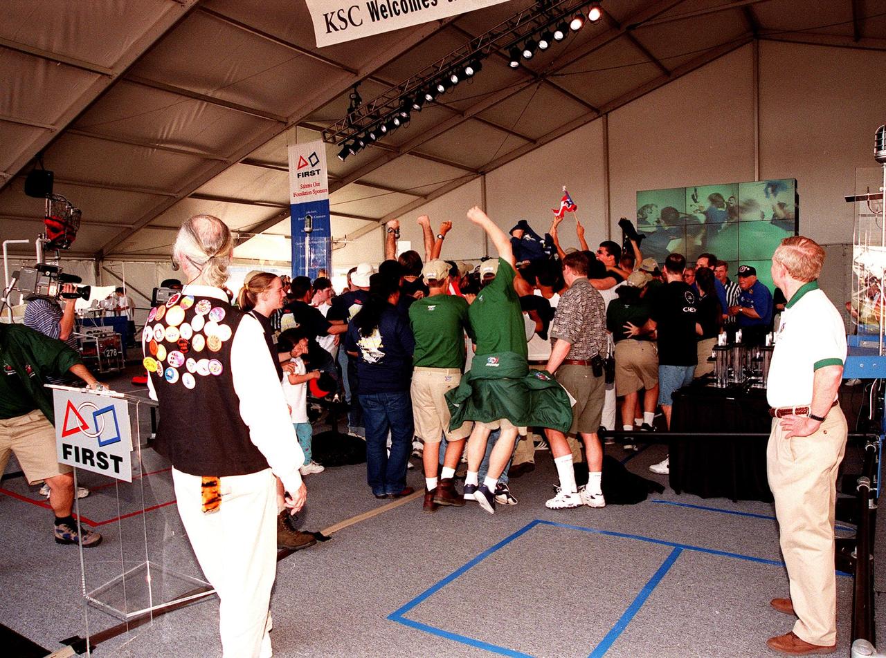 At the award ceremony for the 1999 FIRST Southeastern Regional robotic competition held at KSC, the winning teams, from Miami and San German, Puerto Rico, jump for joy and wave a flag. In the foreground, at left, are Woody Flowers, national advisor to FIRST, and at right, Roy Bridges, KSC director. FIRST is a nonprofit organization, For Inspiration and Recognition of Science and Technology, that sponsors the event pitting gladiator robots against each other in an athletic-style competition. The FIRST robotics competition is designed to provide students with a hands-on, inside look at engineering and other professional careers, pairing high school students with engineer mentors and corporations. The regional event comprised 27 teams. Along with the championship award, 15 other awards were presented