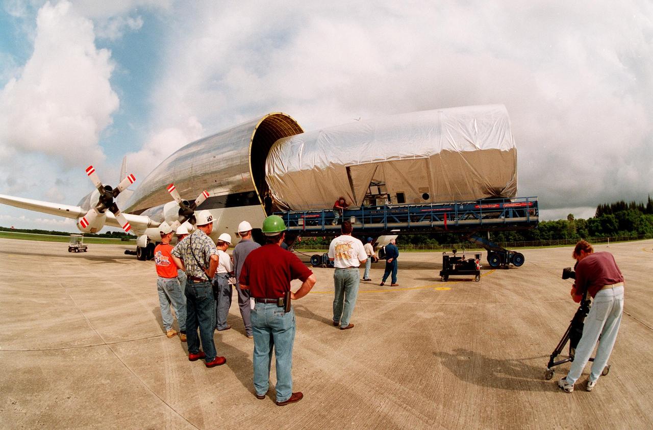 KENNEDY SPACE CENTER, FLA. -- At KSC's Shuttle Landing Facility, workers watch as a S0 (S Zero) truss segment built for the International Space Station (ISS) is moved out of the "Super Guppy" aircraft that brought it to KSC from Boeing in Huntington Beach, Calif. At right a cameraman records the exercise. The truss segment, which will become the backbone of the orbiting ISS, is a 44by 15-foot structure weighing 30,800 pounds when fully outfitted and ready for launch. It will be at the center of the ISS 10-truss, girderlike structure that will ultimately extend the length of a football field. Eventually the S0 truss will be attached to the U.S. Lab, "Destiny," which is scheduled to be added to the ISS in April 2000. Later, other trusses will be attached to the S0 on-orbit. During processing at KSC, the Canadian Mobile Transporter will be installed on the S0 truss, followed by power distribution system modules, a heat pipe radiator for cooling, computers, and a pair of rate gyroscopes. Four Global Positioning System antennas are already installed. The S0 truss is scheduled to be launched in the first quarter of 2001 on mission STS-108