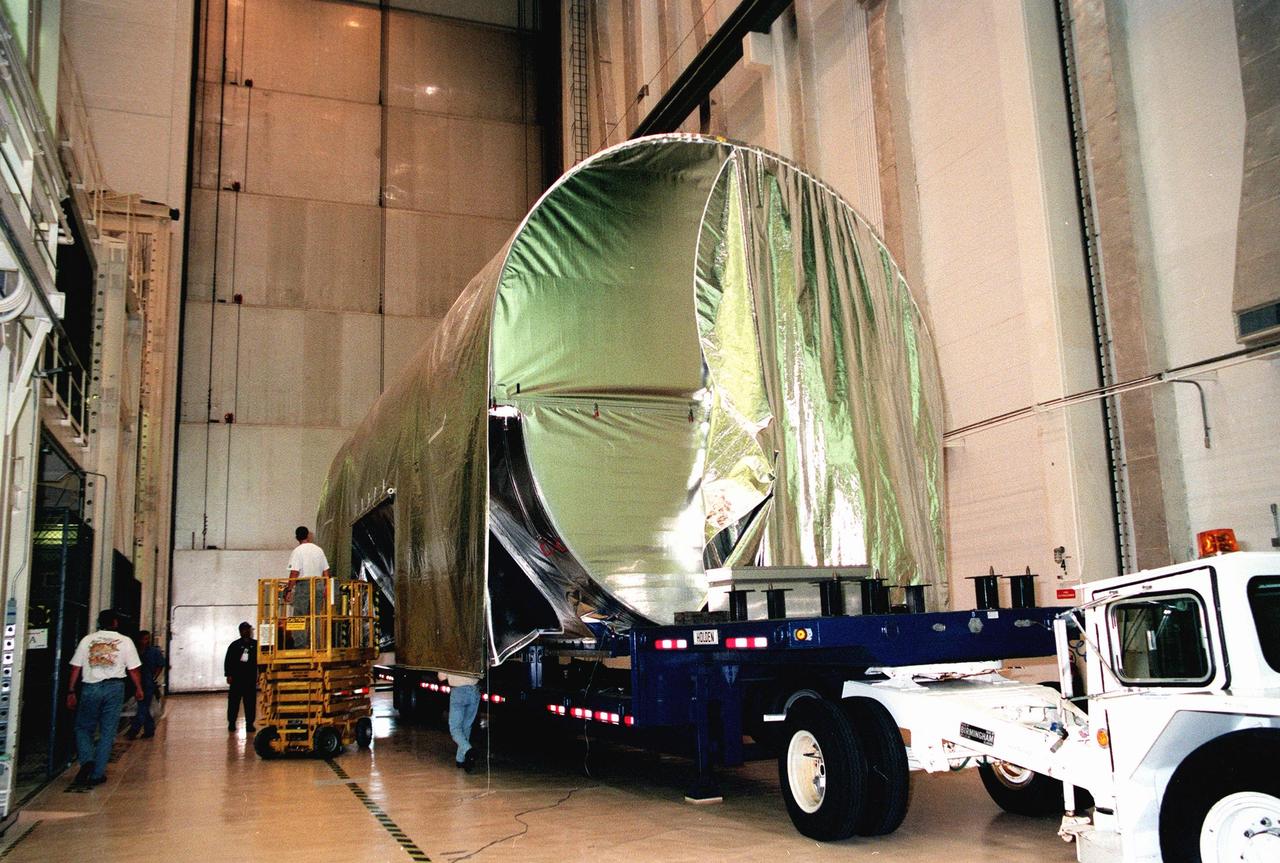 KENNEDY SPACE CENTER, FLA. -- Workers begin removing the cover from the S0 truss segment after it was moved inside the Operations and Checkout Bldg. (O&C) for processing. The truss arrived at the SLF aboard a "Super Guppy" aircraft from Boeing in Huntington, Calif. During processing in the O&C, the S0 truss will have installed the Canadian Mobile Transporter, power distribution system modules, a heat pipe radiator for cooling, computers, and a pair of rate gyroscopes. Four Global Positioning System antennas are already installed. A 44by 15-foot structure weighing 30,800 pounds when fully outfitted and ready for launch, the truss will be at the center of the ISS 10-truss, girderlike structure that will ultimately extend the length of a football field. Eventually the S0 truss will be attached to the U.S. Lab, "Destiny," which is scheduled to be added to the ISS in April 2000. Later, other trusses will be attached to the S0 on-orbit. The S0 truss is scheduled to be launched in the first quarter of 2001 on mission STS-108