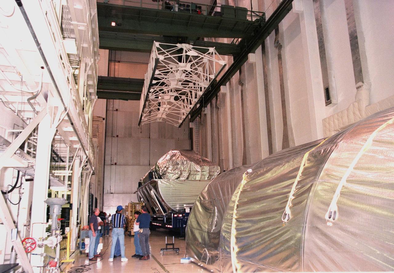 KENNEDY SPACE CENTER, FLA. -- Inside the Operations and Checkout Bldg. (O&C), an overhead crane is centered over the S0 truss segment before lowering. The crane will move it to a workstand in the O&C where it will undergo processing. In the foreground is the protective cover just removed. During the processing, the Canadian Mobile Transporter, power distribution system modules, a heat pipe radiator for cooling, computers, and a pair of rate gyroscopes will be installed. Four Global Positioning System antennas are already installed. A 44by 15-foot structure weighing 30,800 pounds when fully outfitted and ready for launch, the truss will be at the center of the ISS 10-truss, girderlike structure that will ultimately extend the length of a football field. Eventually the S0 truss will be attached to the U.S. Lab, "Destiny," which is scheduled to be added to the ISS in April 2000. Later, other trusses will be attached to the S0 on-orbit. The S0 truss is scheduled to be launched in the first quarter of 2001 on mission STS-108