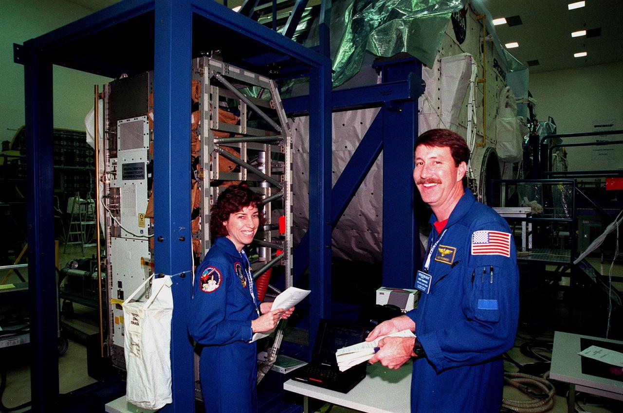 At the SPACEHAB Facility, STS-96 Mission Specialist Ellen Ochoa and Commander Kent Rominger smile for the camera during a payload Interface Verification Test (IVT) for their upcoming mission to the International Space Station. Other crew members at KSC for the IVT are Pilot Rick Husband and Mission Specialists Tamara Jernigan, Dan Barry, Julie Payette and Valery Tokarev of Russia. Mission STS-96 carries the SPACEHAB Logistics Double Module, which will have equipment to further outfit the International Space Station service module and equipment that can be off-loaded from the early U.S. assembly flights. It carries internal logistics and resupply cargo for station outfitting, plus an external Russian cargo crane to be mounted to the exterior of the Russian station segment and used to perform space walking maintenance activities. The double module stowage provides capacity of up to 10,000 lbs. with the ability to accommodate powered payloads, four external rooftop stowage locations, four double-rack locations (two powered), up to 61 bulkhead-mounted middeck locker locations, and floor storage for large unique items and Soft Stowage. STS-96 is targeted to launch May 20 about 9:32 a.m. EDT