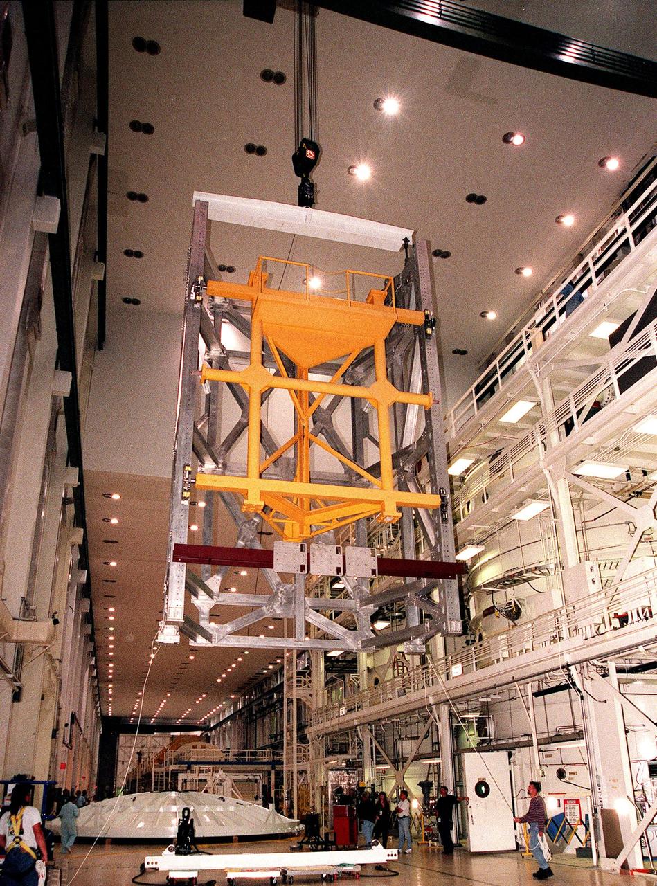KENNEDY SPACE CENTER, FLA. -- In the Operations and Checkout Building's high bay, a crane lifts the Rotation Handling Fixture (RHF) and simulated module during a test. Under normal operation, the RHF will hold a pressurized module intended for the International Space Station, lifting it up and into an altitude chamber for leak testing. The chamber was recently reactivated after a 24-year hiatus. Originally, two chambers were built to test Apollo Program flight hardware. They were last used in 1975 during the Apollo-Soyuz Test Project. In 1997, in order to increase the probability of successful missions aboard the ISS, NASA decided to perform leak tests on ISS pressurized modules at the launch site. After installation of new vacuum pumping equipment and controls, a new control room, and a new rotation and handling fixture, the chamber again became operational in February 1999. The chamber, which is 33 feet in diameter and 50 feet tall, is constructed of stainless steel. The rotation handling fixture is aluminum. The first module that will be tested for leaks is the U.S. Laboratory. No date has been determined for the test