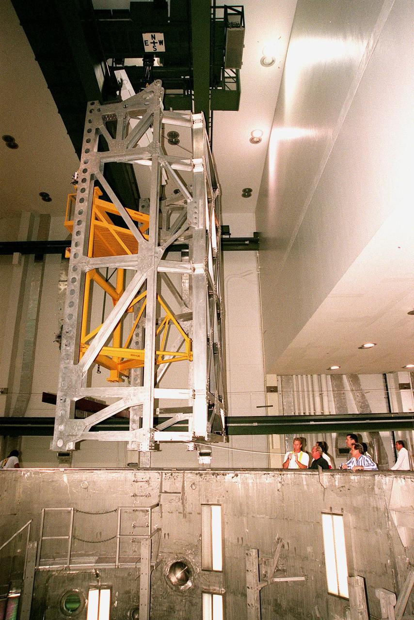 KENNEDY SPACE CENTER, FLA. -- In the Operations and Checkout Building's high bay, the Rotation Handling Fixture (RHF), with a simulated module attached, is lowered by crane into the altitude chamber below during a test. Under normal operation, the RHF will hold a pressurized module intended for the International Space Station, depositing it into the altitude chamber for leak testing. The chamber was recently reactivated after a 24-year hiatus. Originally, two chambers were built to test Apollo Program flight hardware. They were last used in 1975 during the Apollo-Soyuz Test Project. In 1997, in order to increase the probability of successful missions aboard the ISS, NASA decided to perform leak tests on ISS pressurized modules at the launch site. After installation of new vacuum pumping equipment and controls, a new control room, and a new rotation and handling fixture, the chamber again became operational in February 1999. The chamber, which is 33 feet in diameter and 50 feet tall, is constructed of stainless steel. The rotation handling fixture is aluminum. The first module that will be tested for leaks is the U.S. Laboratory. No date has been determined for the test