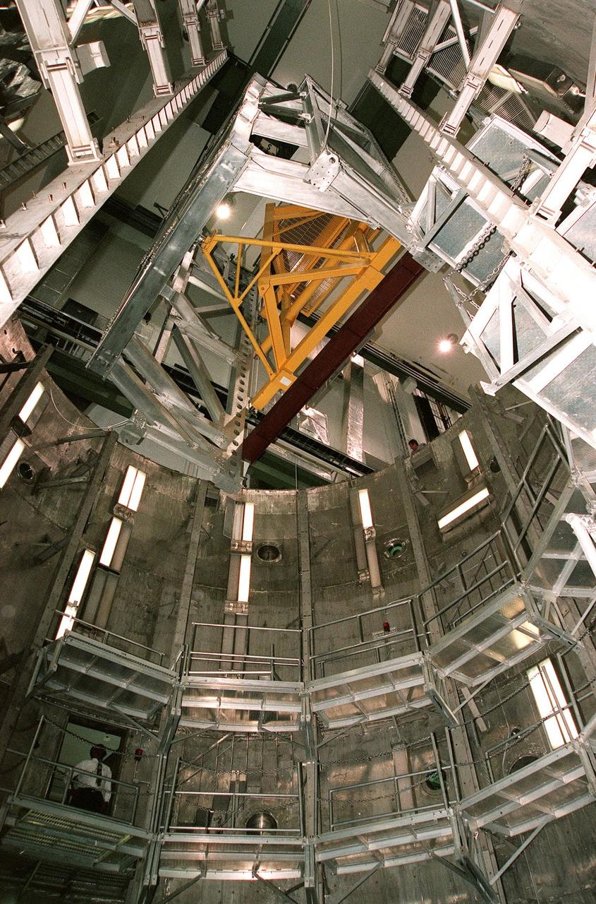 KENNEDY SPACE CENTER, FLA. -- Viewed from inside the altitude chamber in the Operations and Checkout Building's high bay, the Rotation Handling Fixture (RHF), with a simulated module attached, is lowered during a test. Under normal operation, the RHF will hold a pressurized module intended for the International Space Station, depositing it into the altitude chamber for leak testing. The chamber was recently reactivated after a 24-year hiatus. Originally, two chambers were built to test Apollo Program flight hardware. They were last used in 1975 during the Apollo-Soyuz Test Project. In 1997, in order to increase the probability of successful missions aboard the ISS, NASA decided to perform leak tests on ISS pressurized modules at the launch site. After installation of new vacuum pumping equipment and controls, a new control room, and a new rotation and handling fixture, the chamber again became operational in February 1999. The chamber, which is 33 feet in diameter and 50 feet tall, is constructed of stainless steel. The rotation handling fixture is aluminum. The first module that will be tested for leaks is the U.S. Laboratory. No date has been determined for the test