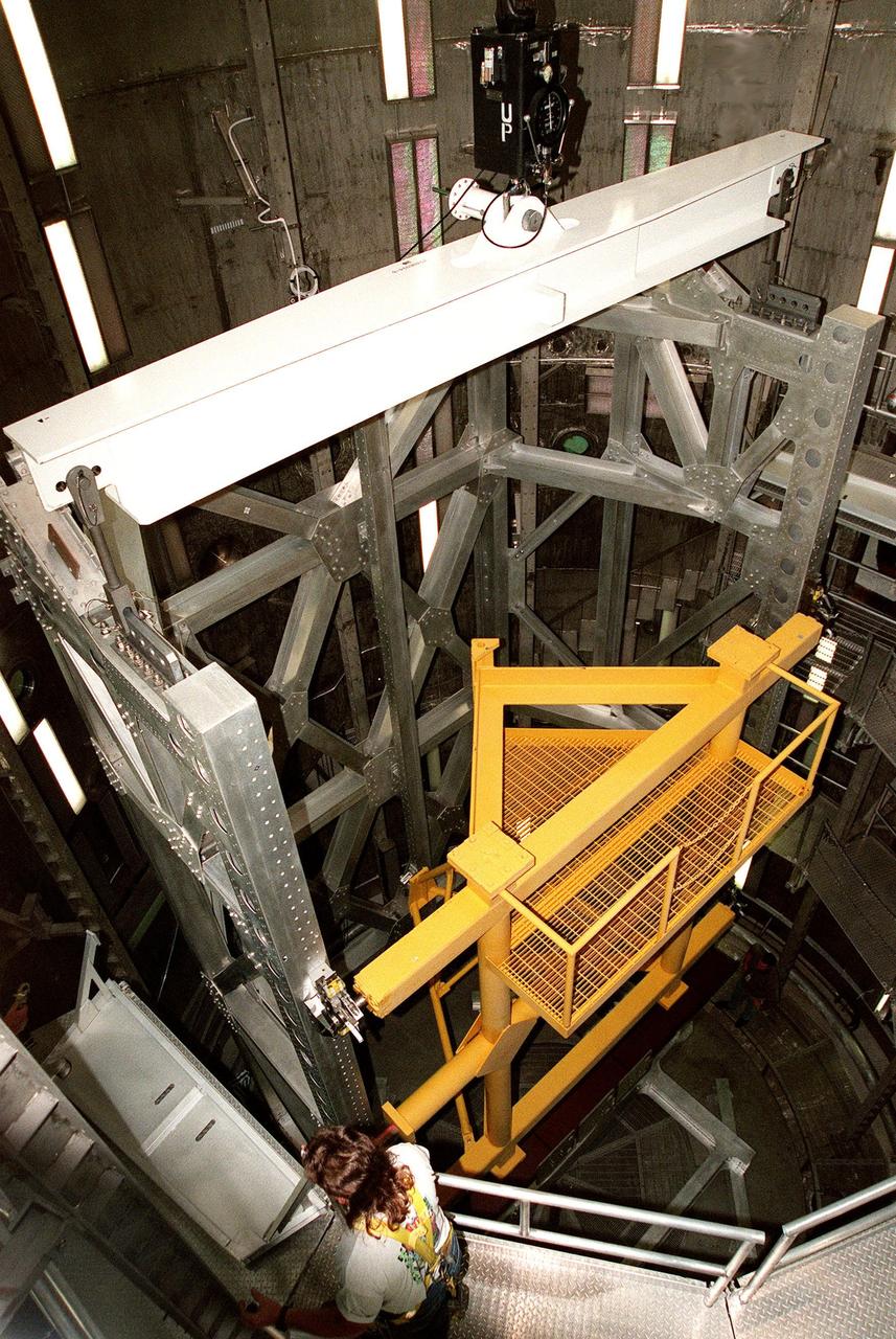KENNEDY SPACE CENTER, FLA. -- In the Operations and Checkout Building's high bay, the Rotation Handling Fixture (RHF), with a simulated module attached, is viewed from above the altitude chamber into which it was lowered during a test. Under normal operation, the RHF will hold a pressurized module intended for the International Space Station, depositing it into the altitude chamber for leak testing. The chamber was recently reactivated after a 20-year hiatus. Originally, two chambers were built to test Apollo Program flight hardware. They were last used in 1975 during the Apollo-Soyuz Test Project. In 1997, in order to increase the probability of successful missions aboard the ISS, NASA decided to perform leak tests on ISS pressurized modules at the launch site. After installation of new vacuum pumping equipment and controls, a new control room, and a new rotation and handling fixture, the chamber again became operational in February 1999. The chamber, which is 33 feet in diameter and 50 feet tall, is constructed of stainless steel. The rotation handling fixture is aluminum. The first module that will be tested for leaks is the U.S. Laboratory. No date has been determined for the test