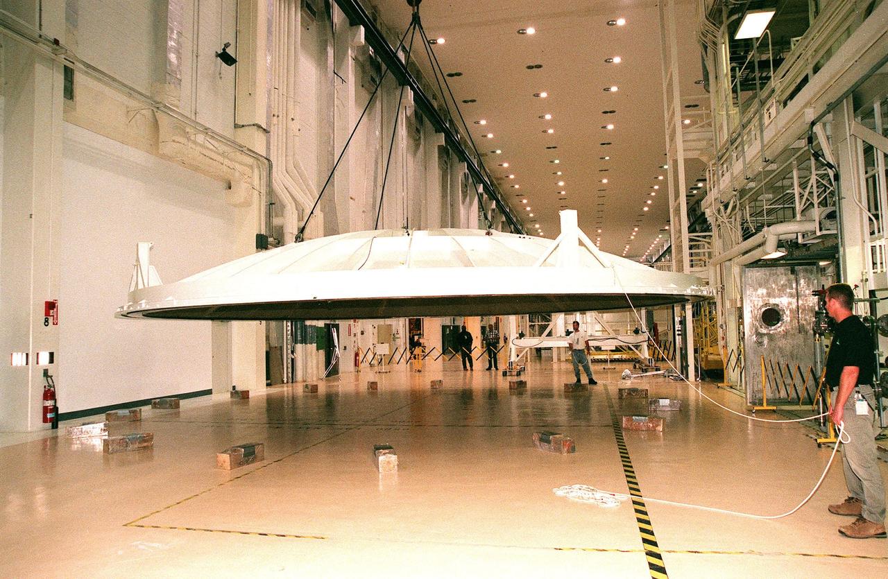 KENNEDY SPACE CENTER, FLA. -- An overhead crane lifts the saucer-like 27.5-ton lid of an altitude chamber in the Operations and Checkout Building high bay. The chamber was recently reactivated, after a 24-year hiatus, to perform leak tests on International Space Station pressurized modules at the launch site. Originally, two chambers were built to test Apollo Program flight hardware. They were last used in 1975 during the Apollo-Soyuz Test Project. After installation of new vacuum pumping equipment and controls, a new control room, and a new rotation handling fixture, the chamber again became operational in February 1999. The chamber, which is 33 feet in diameter and 50 feet tall, is constructed of stainless steel. The first module that will be tested for leaks is the U.S. Laboratory. No date has been determined for the test