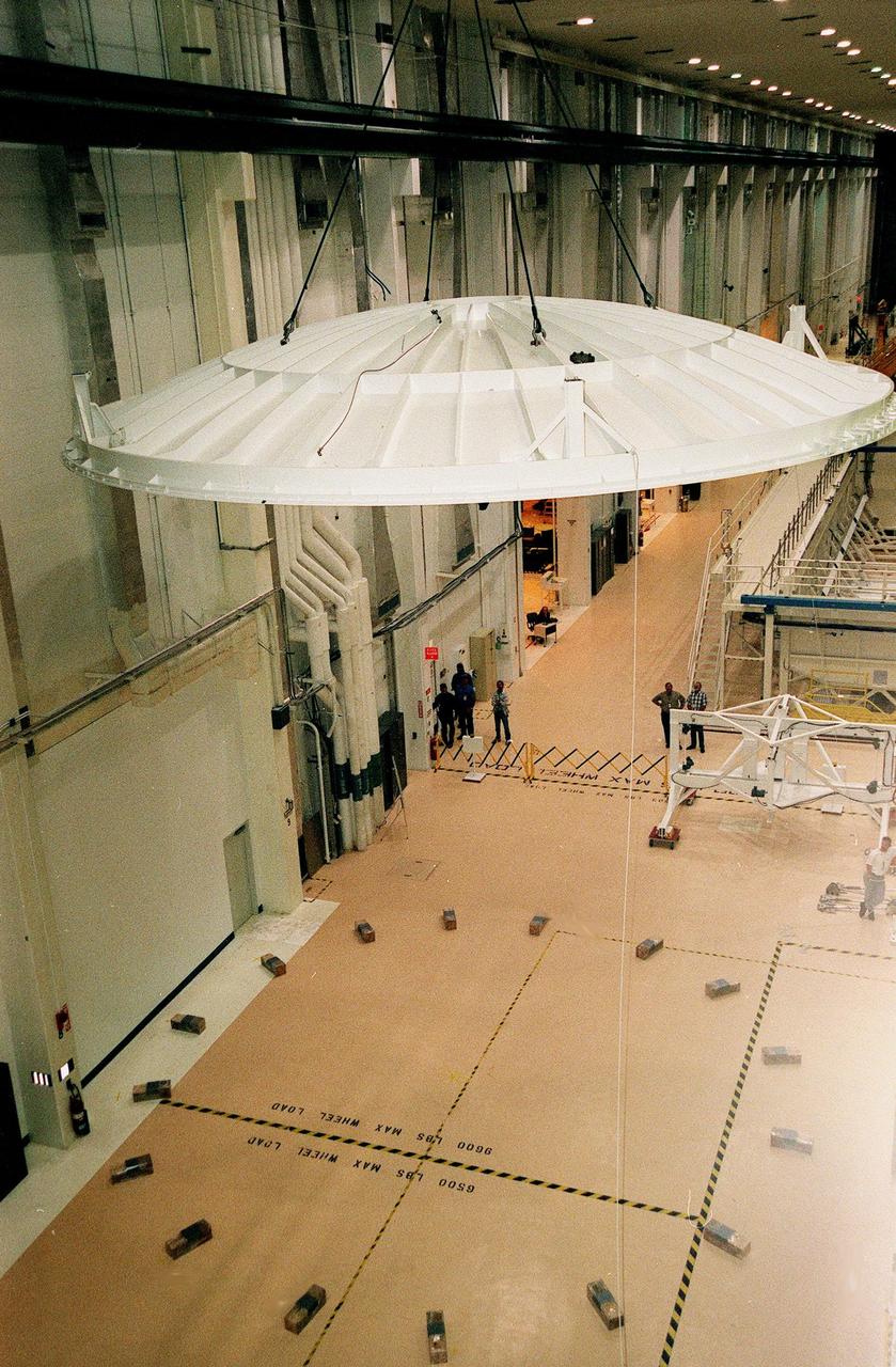 KENNEDY SPACE CENTER, FLA. -- Looking as if poised in flight, the saucer-like lid of an altitude chamber is lifted from the floor in the Operations and Checkout Building high bay to its place on top of the chamber. The chamber was recently reactivated, after a 24-year hiatus, to perform leak tests on International Space Station pressurized modules at the launch site. Originally, two chambers were built to test Apollo Program flight hardware. They were last used in 1975 during the Apollo-Soyuz Test Project. After installation of new vacuum pumping equipment and controls, a new control room, and a new rotation handling fixture, the chamber again became operational in February 1999. The chamber, which is 33 feet in diameter and 50 feet tall, is constructed of stainless steel. The first module that will be tested for leaks is the U.S. Laboratory. No date has been determined for the test