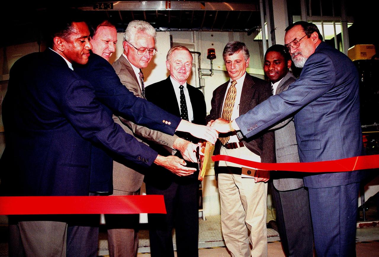 KENNEDY SPACE CENTER, FLA. -- Cutting a red ribbon for the unveiling of a newly renovated altitude chamber are (left to right) Tommy Mack, project manager, NASA; Steve Francois, director, Space Station and Shuttle Payloads; Sterling Walker, director, Engineering Development; Roy Bridges, director, Kennedy Space Center; Jay Greene, International Space Station manager for Technical; Michael Terry, project manager, Boeing; and Terry Smith, director of Engineering, Boeing Space Coast Operations. The chamber was reactivated, after a 24-year hiatus, to perform leak tests on International Space Station pressurized modules at the launch site. Originally, two chambers were built to test the Apollo command and lunar service modules. They were last used in 1975 during the Apollo-Soyuz Test Project. After installation of new vacuum pumping equipment and controls, a new control room, and a new rotation handling fixture, the chamber again became operational in February 1999. The chamber, which is 33 feet in diameter and 50 feet tall, is constructed of stainless steel. The first module that will be tested for leaks is the U.S. Laboratory. No date has been determined for the test