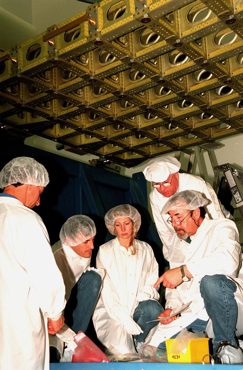 At Astrotech, Titusville, Fla., discussing the International Cargo Carrier (ICC) overhead are Charles Franca, with Johnson Space Center (JSC); Robert Wilkes, with Lockheed Martin; Lora Lawrence, with JSC; Carl Figiel and Harald Schnier, with Daimler-Chrysler Aerospace (DASA). The nonpressurized ICC fits inside the payload bay of the orbiter. The ICC will carry the SPACEHAB Oceaneering Space System Box (SHOSS), a logistics items carrier. SHOSS can hold a maximum of 400 pounds of equipment and will carry items to be used during STS-96 and future ISS assembly flights. Also aboard the ICC will be the ORU Transfer Device (OTD), a U.S.-built crane that will be stowed on Unity for use during future ISS assembly missions. The ICC will fly on mission STS-96, targeted for launch on May 20