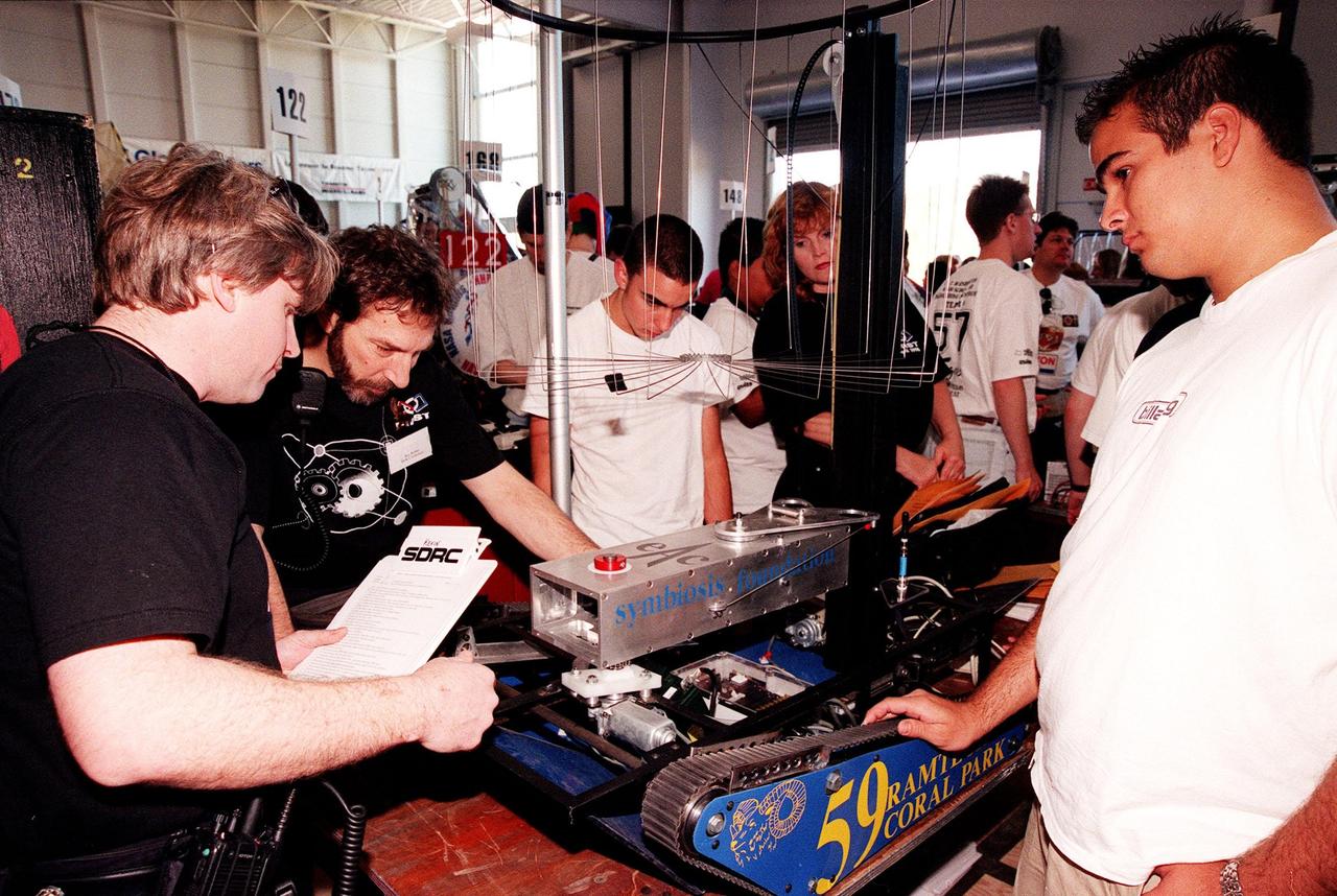 Students look over one of the robots to compete in the 1999 Southeastern Regional robotic competition being held at Kennedy Space Center March 4-6. Thirty schools from around the country have converged at KSC for the event that pits the team-built gladiator robots against each other in an athletic-style competition. KSC is hosting the event being sponsored by the nonprofit organization For Inspiration and Recognition of Science and Technology, known as FIRST. The FIRST robotics competition is designed to provide students with a hands-on, inside look at engineering and other professional careers