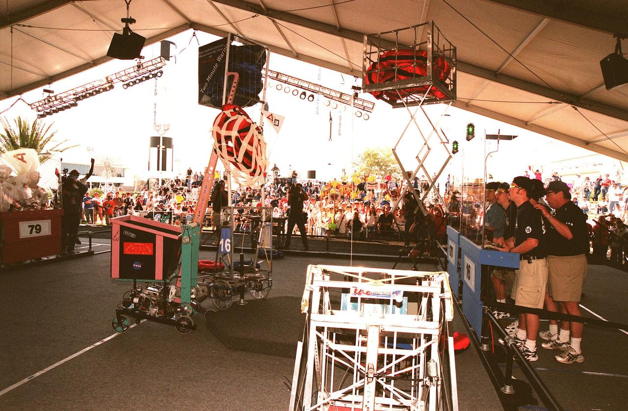 Robots, maneuvered by student teams behind protective walls, raise their caches of pillow-like disks to earn points in competition while spectators in the bleachers and on the sidelines cheer their favorite teams. Held at the KSC Visitor Complex, the 1999 Southeastern Regional robotic competition, sponsored by the nonprofit organization For Inspiration and Recognition of Science and Technology, known as FIRST, comprises 27 teams pairing high school students with engineer mentors and corporations, pitting gladiator robots against each other in an athletic-style competition. Powered by 12-volt batteries and operated by remote control, the robotic gladiators spend two minutes each trying to grab, claw and hoist the pillows onto their machines. Teams play defense by taking away competitors' pillows and generally harassing opposing machines. The FIRST robotics competition is designed to provide students with a hands-on, inside look at engineering and other professional careers