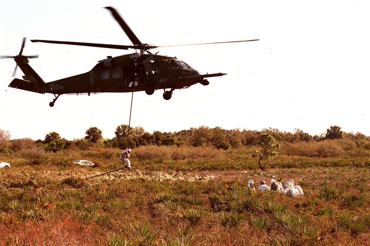 KENNEDY SPACE CENTER, FLA. -- During a simulated rescue mission in the woods near the Shuttle Landing Facility (SLF), a fire/rescue worker practices disembarking from an Air Force HH-60 helicopter. The KSC response team is training for the unlikely scenario of a Shuttle mishap at the SLF. The Mode 7 simulation of an astronaut rescue exercises all aspects of command and control, search and rescue, and medical procedures required for a successful rescue. The remote location of the mock-up prevents a totally land-based crew rescue, and calls on a NASA UH-1 helicopter to locate the site and four Air Force HH-60 helicopters to drop emergency equipment and fire/rescue workers to prepare the "crew" for preliminary traige. The helicopters are used later to remove the crew five astronaut candidates, one representative from the Vehicle Integration Test office, and one fire/rescue worker. The exercise will conclude with airlifted "patients" arriving safely in the emergency rooms of participating area hospitals