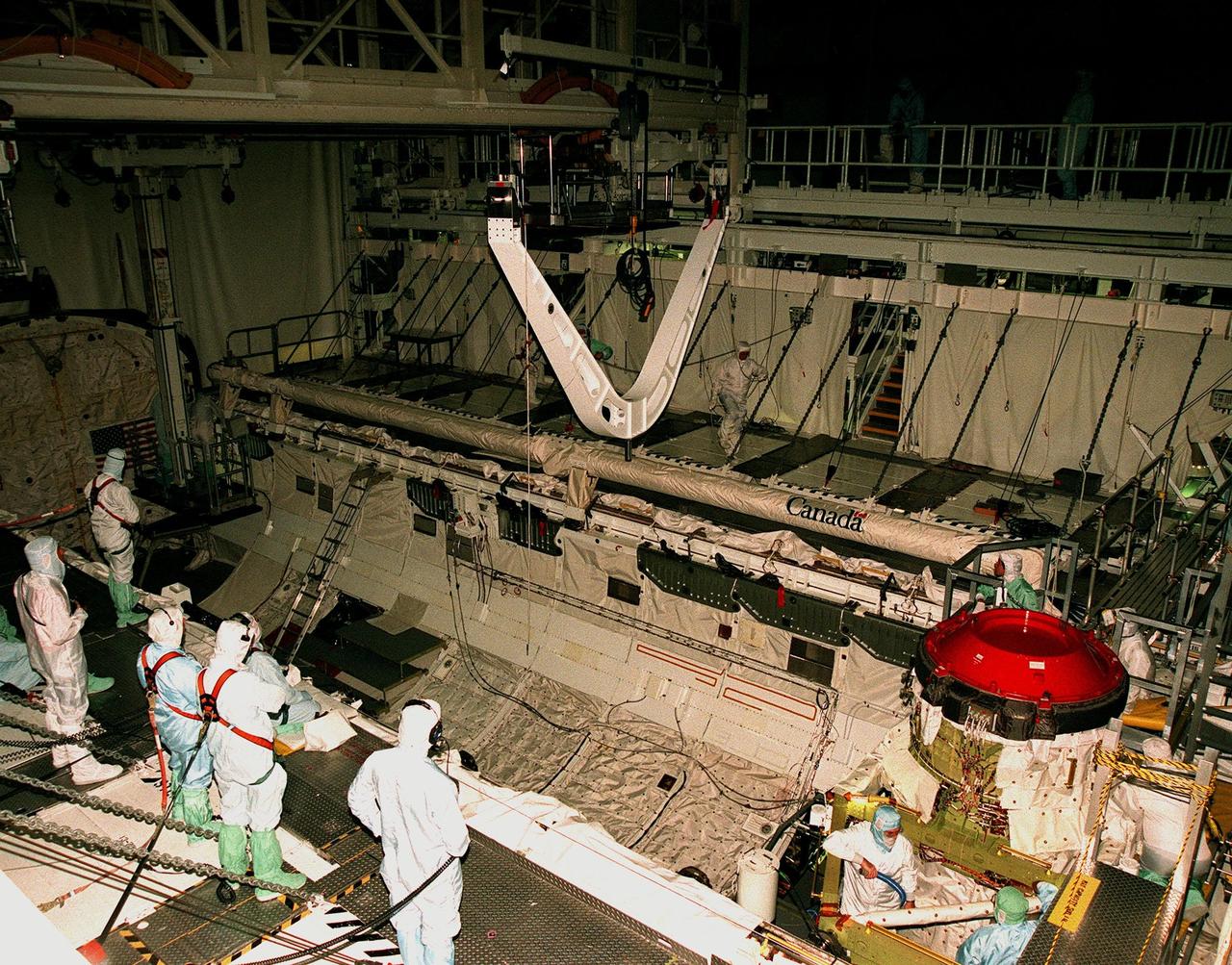 KENNEDY SPACE CENTER, FLA. -- Workers in the Orbiter Processing Facility (OPF) Bay 1 watch as the Keel Yoke Device (KYD) is lowered by crane into the open payload bay of the orbiter Discovery. The KYD will support the International Cargo Carrier (ICC) to be installed in the orbiter for mission STS-96. The ICC will carry unpressurized cargo such as the external Russian cargo crane known as STRELA, the SPACEHAB Oceaneering Space System Box (SHOSS), which is a logistics items carrier, and an ORU Transfer Device (OTD), a U.S.-built crane that will be stowed on the station for use during future ISS assembly missions. The primary payload of STS-96 is the SPACEHAB Double Module, an element of the International Space Station. . STS-96 is targeted for launch on May 20 at 9:32 a.m. from Launch Pad 39B