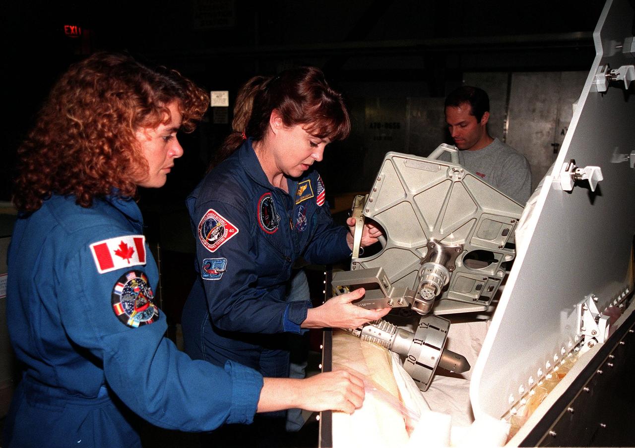 In the Orbiter Processing Facility bay 1, STS-96 Mission Specialists (left) Julie Payette, with the Canadian Space Agency, and Tamara Jernigan, Ph.D., look over the foot restraint used during space walks. The STS-96 crew is at KSC to take part in a Crew Equipment Interface Test. The other crew members are Commander Kent V. Rominger, Pilot Rick Douglas Husband, and Mission Specialists Ellen Ochoa (Ph.D), Daniel Barry (M.D., Ph.D.), and Valery Ivanovich Tokarev, who represents the Russian Space Agency. The primary payload of STS-96 is the SPACEHAB Double Module. In addition, the Space Shuttle will carry unpressurized cargo such as the external Russian cargo crane known as STRELA; the Spacehab Oceaneering Space System Box (SHOSS), which is a logistics items carrier; and an ORU Transfer Device (OTD), a U.S.-built crane that will be stowed on the station for use during future ISS assembly missions. These cargo items will be stowed on the International Cargo Carrier, fitted inside the payload bay behind the SPACEHAB module. STS-96 is targeted for launch on May 24 from Launch Pad 39B