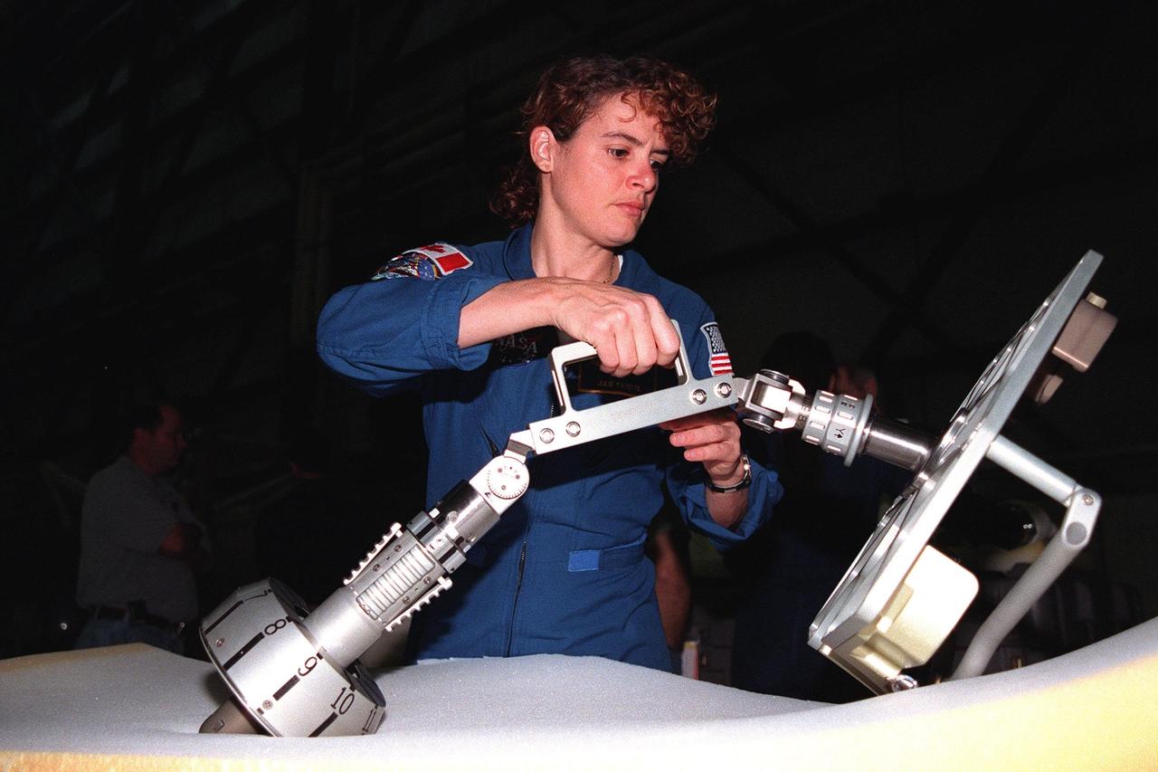 In the Orbiter Processing Facility bay 1, STS-96 Mission Specialist Julie Payette, with the Canadian Space Agency, maneuvers a foot restraint used during space walks. The STS-96 crew is at KSC to take part in a Crew Equipment Interface Test. The other crew members are Commander Kent V. Rominger, Pilot Rick Douglas Husband and Mission Specialists Ellen Ochoa (Ph.D.), Tamara E. Jernigan (Ph.D.), Daniel Barry (M.D., Ph.D.), and Valery Ivanovich Tokarev, who represents the Russian Space Agency. The primary payload of STS-96 is the SPACEHAB Double Module. In addition, the Space Shuttle will carry unpressurized cargo such as the external Russian cargo crane known as STRELA; the Spacehab Oceaneering Space System Box (SHOSS), which is a logistics items carrier; and an ORU Transfer Device (OTD), a U.S.-built crane that will be stowed on the station for use during future ISS assembly missions. These cargo items will be stowed on the International Cargo Carrier, fitted inside the payload bay behind the SPACEHAB module. STS-96 is targeted for launch on May 24 from Launch Pad 39B