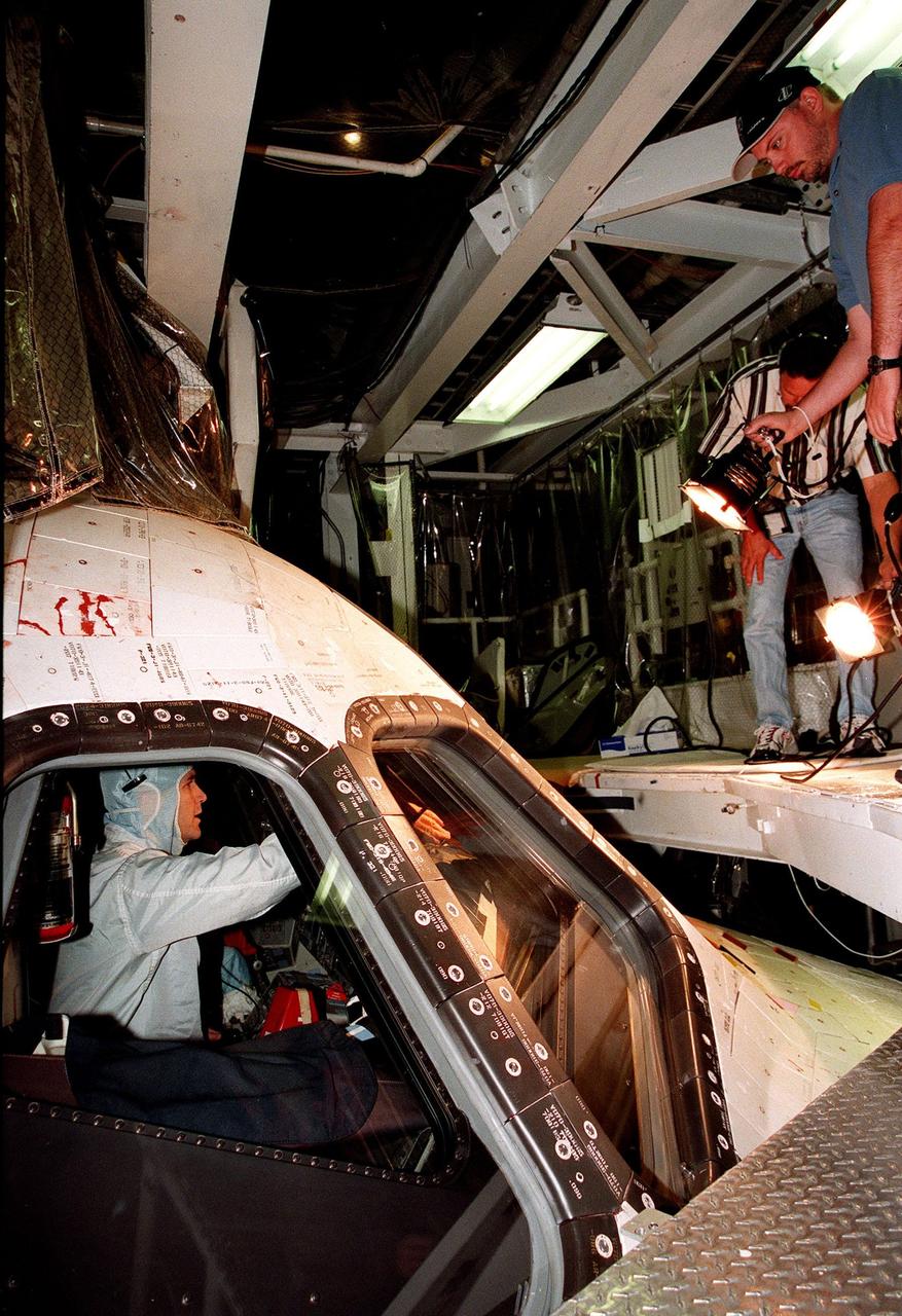 STS-96 Pilot Rick Douglas Husband checks the windows of the orbiter Discovery in the Orbiter Processing Facility bay 1 as a worker shines a light through them. The STS-96 crew is at KSC to take part in a Crew Equipment Interface Test. The other crew members are Pilot Rick Douglas Husband and Mission Specialists Ellen Ochoa (Ph.D.), Tamara E. Jernigan (Ph.D.), Daniel Barry (M.D., Ph.D.), Julie Payette and Valery Ivanovich Tokarev. Payette represents the Canadian Space Agency and Tokarev the Russian Space Agency. The primary payload of STS-96 is the SPACEHAB Double Module. In addition, the Space Shuttle will carry unpressurized cargo such as the external Russian cargo crane known as STRELA; the Spacehab Oceaneering Space System Box (SHOSS), which is a logistics items carrier; and an ORU Transfer Device (OTD), a U.S.-built crane that will be stowed on the station for use during future ISS assembly missions. These cargo items will be stowed on the International Cargo Carrier, fitted inside the payload bay behind the SPACEHAB module. STS-96 is targeted for launch on May 24 from Launch Pad 39B