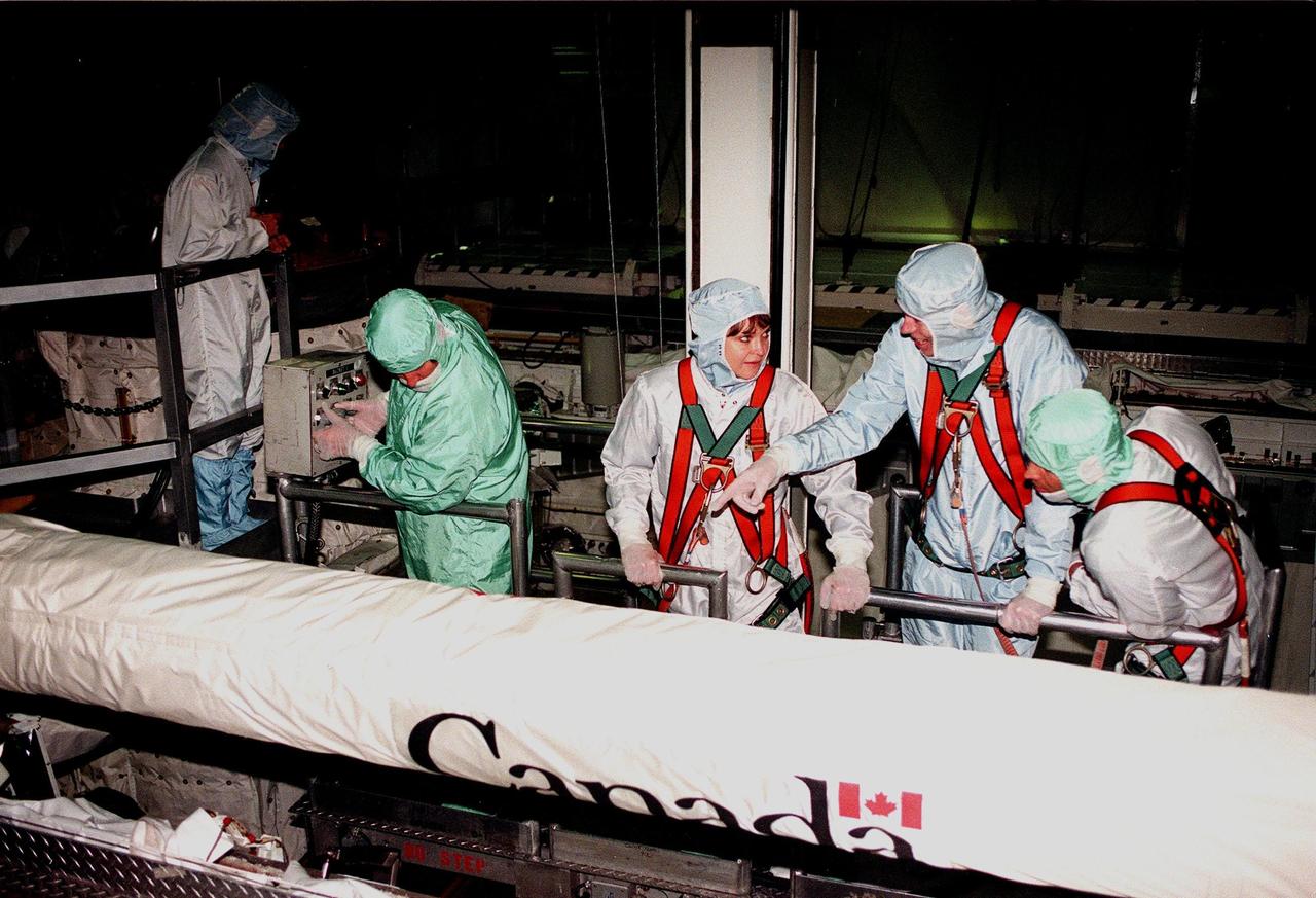 In the Orbiter Processing Facility bay 1, STS-96 crew members look at the Canadian arm in the payload bay of the orbiter Discovery. Standing in a bucket controlled by a KSC worker, are (from left) Mission Specialist Tamara E. Jernigan (Ph.D), Daniel Barry (M.D., Ph.D.), and Valery Ivanovich Tokarev, who represents the Russian Space Agency. The STS-96 crew is at KSC to take part in a Crew Equipment Interface Test. The other crew members are Commander Kent V. Rominger, Pilot Rick Douglas Husband and Mission Specialists Ellen Ochoa (Ph.D.) and Julie Payette, with the Canadian Space Agency. The primary payload of STS-96 is the SPACEHAB Double Module. In addition, the Space Shuttle will carry unpressurized cargo such as the external Russian cargo crane known as STRELA; the Spacehab Oceaneering Space System Box (SHOSS), which is a logistics items carrier; and an ORU Transfer Device (OTD), a U.S.-built crane that will be stowed on the station for use during future ISS assembly missions. These cargo items will be stowed on the International Cargo Carrier, fitted inside the payload bay behind the SPACEHAB module. STS-96 is targeted for launch on May 24 from Launch Pad 39B