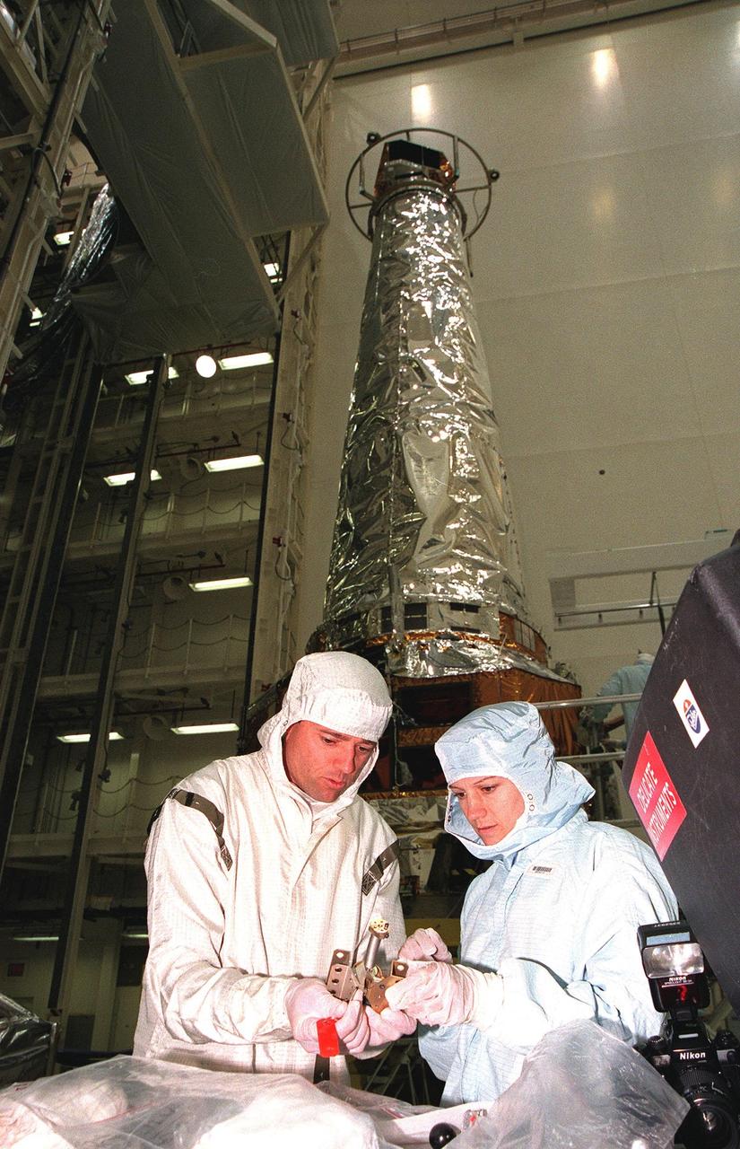 In the Vertical Processing Facility, STS-93 Pilot Jeffrey S. Ashby and Commander Eileen M. Collins look at a hinge used on the solar panels of the Chandra X-ray Observatory. Members of the STS-93 crew are at KSC for payload familiarization. Also participating are Mission Specialists Catherine G. Coleman and Michel Tognini of France, representing the Centre National d'Etudes Spatiales (CNES). Collins is the first woman to serve as a shuttle mission commander. She was the first woman pilot of a Space Shuttle, on mission STS-63, and also served as pilot on mission STS-84. The fifth member of the crew is Mission Specialist Steven A. Hawley. Chandra is scheduled for launch July 9 aboard Space Shuttle Columbia, on mission STS-93 . Formerly called the Advanced X-ray Astrophysics Facility, Chandra comprises three major elements: the spacecraft, the science instrument module (SIM), and the world's most powerful X-ray telescope. Chandra will allow scientists from around the world to see previously invisible black holes and high-temperature gas clouds, giving the observatory the potential to rewrite the books on the structure and evolution of our universe