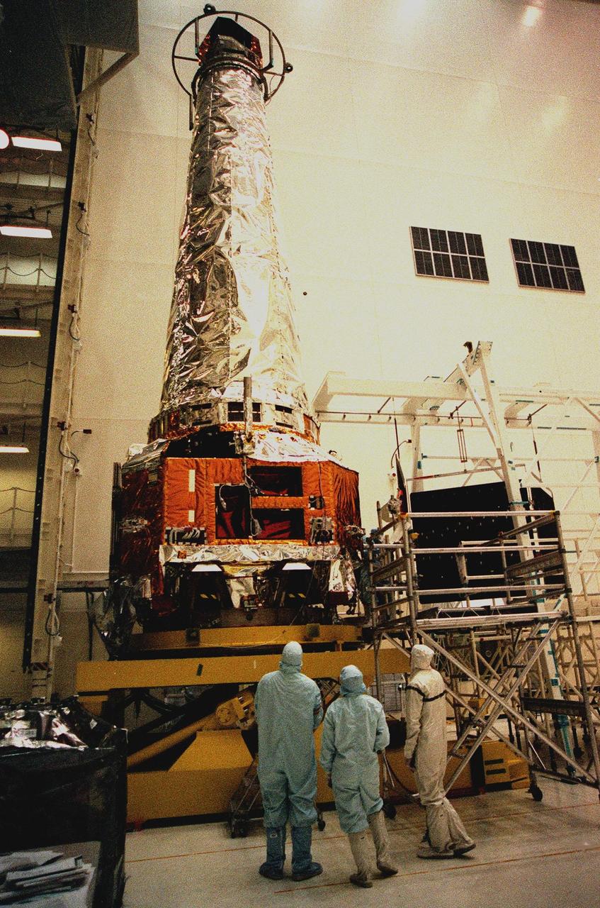 A TRW technician joins STS-93 Commander Eileen Collins (center) and Pilot Jeffrey S. Ashby (right) as they observe the Chandra X-ray Observatory on its work stand inside the Vertical Processing Facility. Other members of the STS-93 crew who are at KSC for payload familiarization are Mission Specialists Catherine G. Coleman and Michel Tognini of France, who represents the Centre National d'Etudes Spatiales (CNES). Collins is the first woman to serve as a shuttle mission commander. She was the first woman pilot of a Space Shuttle, on mission STS-63, and also served as pilot on mission STS-84. The fifth member of the crew is Mission Specialist Steven A. Hawley. Chandra is scheduled for launch July 9 aboard Space Shuttle Columbia, on mission STS-93 . Formerly called the Advanced X-ray Astrophysics Facility, Chandra comprises three major elements: the spacecraft, the science instrument module (SIM), and the world's most powerful X-ray telescope. Chandra will allow scientists from around the world to see previously invisible black holes and high-temperature gas clouds, giving the observatory the potential to rewrite the books on the structure and evolution of our universe