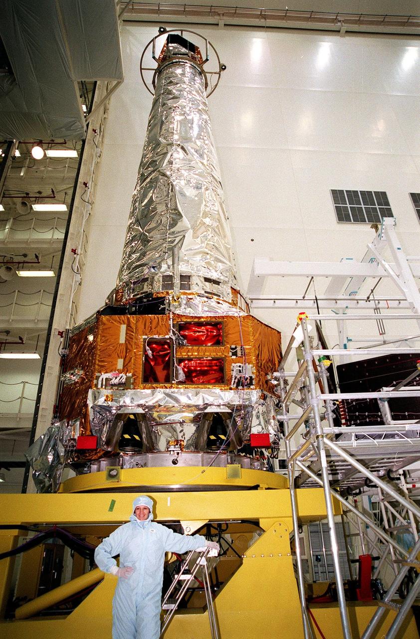 STS-93 Commander Eileen Collins poses at the foot of the Chandra X-ray Observatory during payload familiarization. Other members of the STS-93 crew who are at KSC are Pilot Jeffrey S. Ashby and Mission Specialists Catherine G. Coleman and Michel Tognini of France, who represents the Centre National d'Etudes Spatiales (CNES). Collins is the first woman to serve as a shuttle mission commander. She was the first woman pilot of a Space Shuttle, on mission STS-63, and also served as pilot on mission STS-84. The fifth member of the crew is Mission Specialist Steven A. Hawley. Chandra is scheduled for launch July 9 aboard Space Shuttle Columbia, on mission STS-93 . Formerly called the Advanced X-ray Astrophysics Facility, Chandra comprises three major elements: the spacecraft, the science instrument module (SIM), and the world's most powerful X-ray telescope. Chandra will allow scientists from around the world to see previously invisible black holes and high-temperature gas clouds, giving the observatory the potential to rewrite the books on the structure and evolution of our universe
