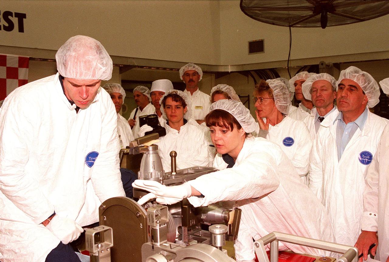 At Astrotech in Titusville, Fla., STS-96 Mission Speciaists Daniel T. Barry (left), Julie Payette (center, with camera), and Tamara E. Jernigan (right, pointing) get a close look at one of the payloads on their upcoming mission. Other crew members are Commander Kent V. Rominger, and Mission Specialists Ellen Ochoa and Valery Ivanovich Tokarev, with the Russian Space Agency. Payette is with the Canadian Space Agency. For the first time, STS-96 will include an Integrated Cargo Carrier (ICC) that will carry a Russian cargo crane, the Strela, to be mounted to the exterior of the Russian station segment on the International Space Station (ISS); the SPACEHAB Oceaneering Space System Box (SHOSS), which is a logistics items carrier; and a U.S.-built crane (ORU Transfer Device, or OTD) that will be stowed on the station for use during future ISS assembly missions. The ICC can carry up to 6,000 lb of unpressurized payload. It was built for SPACEHAB by DaimlerChrysler and RSC Energia of Korolev, Russia. STS-96 is targeted for launch on May 24 from Launch Pad 39B. STS-101 is scheduled to launch in early December 1999