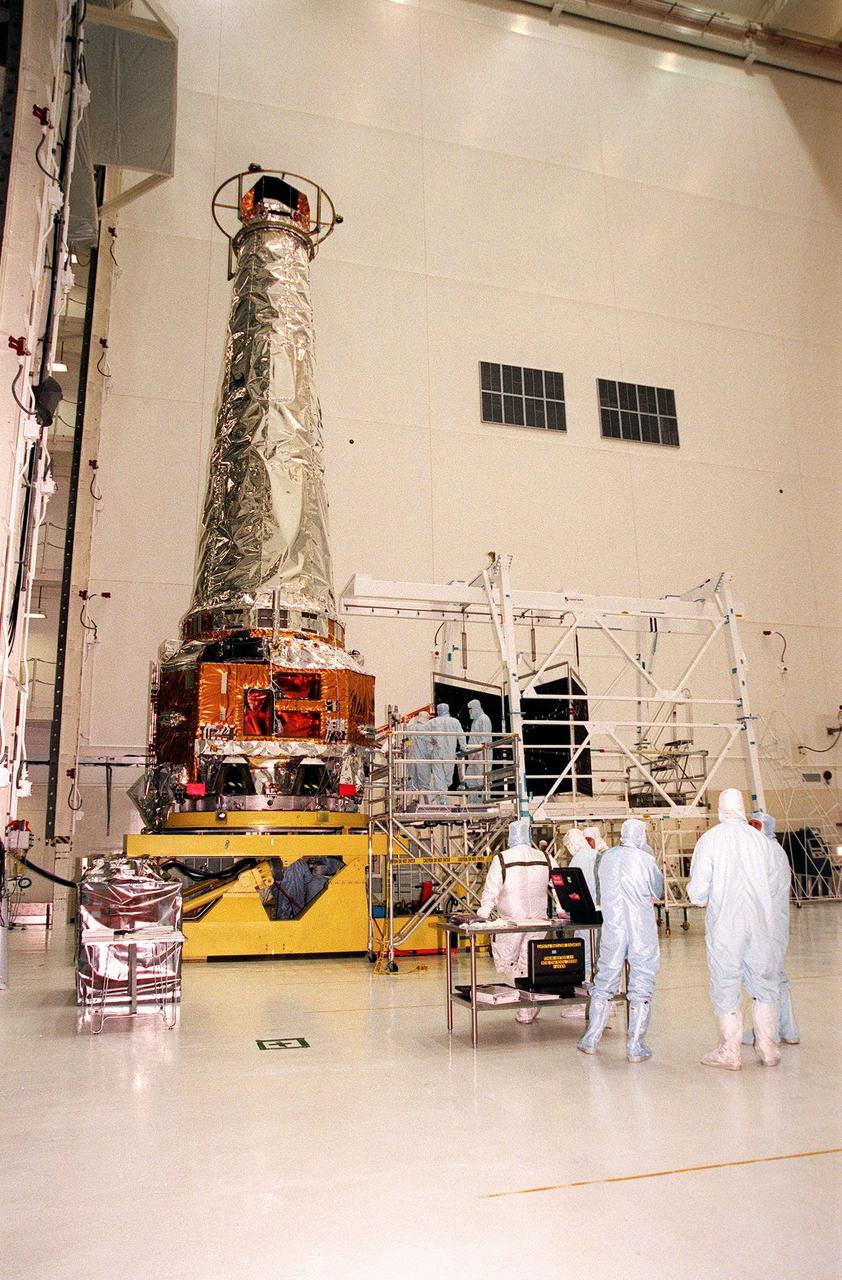 In the Vertical Processing Facility, TRW technicians get ready to attach and deploy a solar panel array on the Chandra X-ray Observatory, which is sitting on a workstand. The panel is to the right. Formerly called the Advanced X-ray Astrophysics Facility, Chandra comprises three major elements: the spacecraft, the science instrument module (SIM), and the world's most powerful X-ray telescope. Chandra will allow scientists from around the world to see previously invisible black holes and high-temperature gas clouds, giving the observatory the potential to rewrite the books on the structure and evolution of our universe. Chandra is scheduled for launch July 9 aboard Space Shuttle Columbia, on mission STS-93