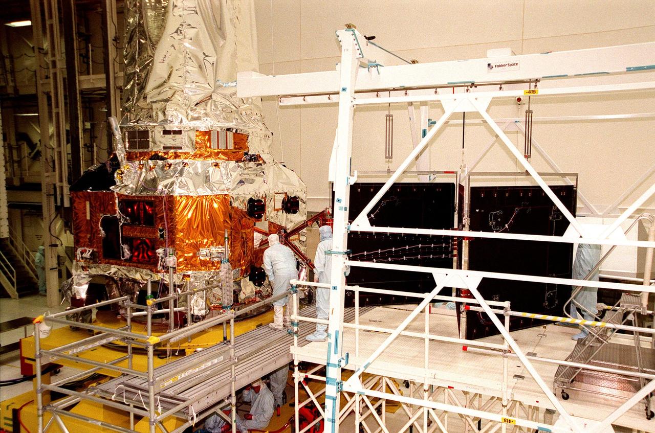 In the Vertical Processing Facility, TRW technicians look at the point of attachment on the Chandra X-ray Observatory, at left, for the solar panel array (behind them). They are getting ready to attach and deploy the solar panel. Formerly called the Advanced X-ray Astrophysics Facility, Chandra comprises three major elements: the spacecraft, the science instrument module (SIM), and the world's most powerful X-ray telescope. Chandra will allow scientists from around the world to see previously invisible black holes and high-temperature gas clouds, giving the observatory the potential to rewrite the books on the structure and evolution of our universe. Chandra is scheduled for launch July 9 aboard Space Shuttle Columbia, on mission STS-93