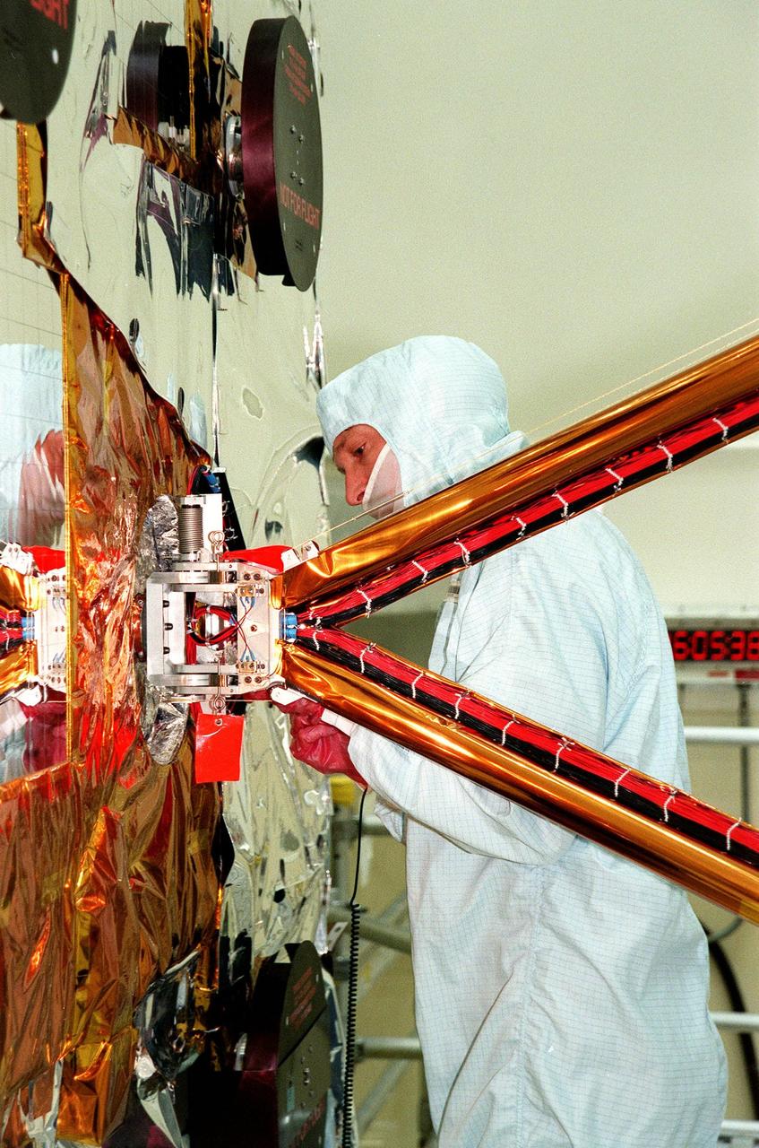 In the Vertical Processing Facility, a TRW technician checks the attachment of the solar panel array (out of sight to the right) to the Chandra X-ray Observatory, at left. Formerly called the Advanced X-ray Astrophysics Facility, Chandra comprises three major elements: the spacecraft, the science instrument module (SIM), and the world's most powerful X-ray telescope. Chandra will allow scientists from around the world to see previously invisible black holes and high-temperature gas clouds, giving the observatory the potential to rewrite the books on the structure and evolution of our universe. Chandra is scheduled for launch July 9 aboard Space Shuttle Columbia, on mission STS-93