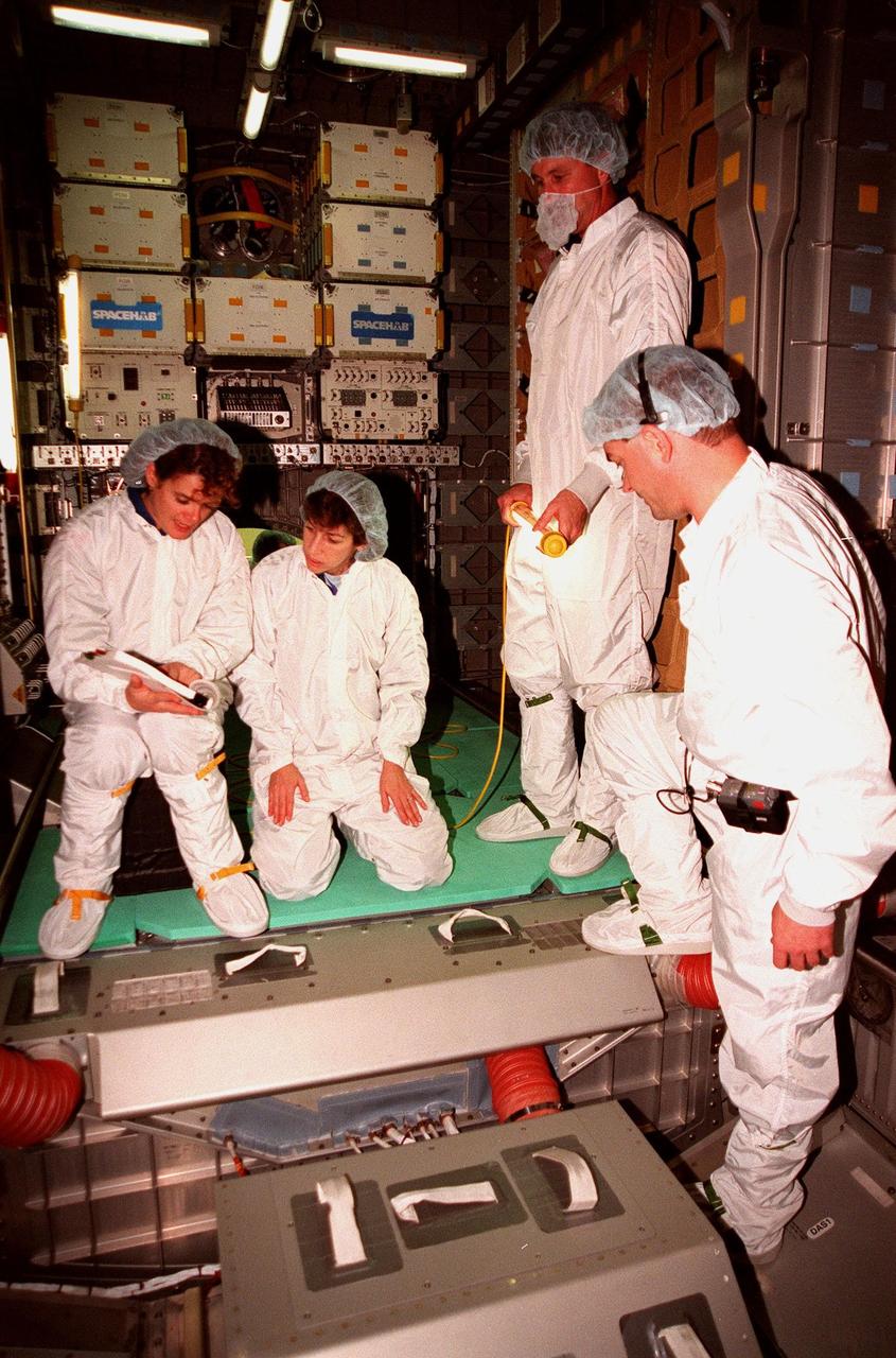 KENNEDY SPACE CENTER, FLA. -- (From left) STS-96 Mission Specialists Julie Payette and Ellen Ochoa, and Commander Kent V. Rominger check out equipment inside the SPACEHAB module. At right is Chris Jaskoika with Boeing SPACEHAB. Members of the STS-96 crew are taking part in a bench review at SPACEHAB as part of familiarization activities for their upcoming mission. The crew also includes Pilot Rick Husband and Mission Specialists Tamara E. Jernigan, Daniel Barry, and Valery Ivanovich Tokarev. Payette is with the Canadian Space Agency and Tokarev with the Russian Space Agency. Mission STS-96 is the second flight in construction of the International Space Station and will include the SPACEHAB. The 10-day mission is targeted for launch on May 24, 1999, at Launch Pad 39B