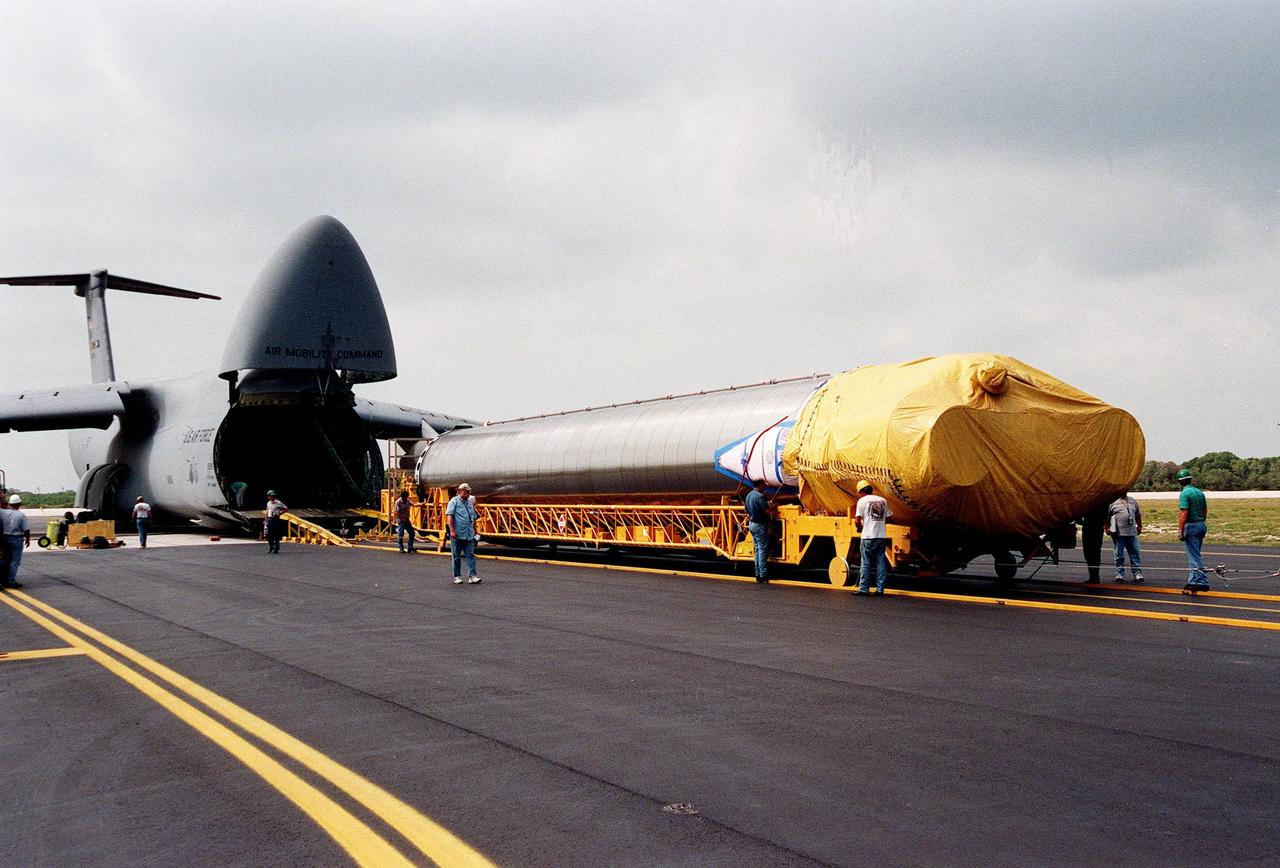 At Cape Canaveral Air Station, workers secure an Atlas IIA rocket on a transporter after offloading it from a U.S. Air Force C-5c (left). The rocket is scheduled to launch the NASA GOES-L satellite from Launch Pad 36A on May 15. Once in orbit, the satellite will become GOES-11, joining GOES-8, GOES-9 and GOES-10 in space. The fourth of a new advanced series of geostationary weather satellites for the National Oceanic and Atmospheric Administration (NOAA), GOES-L is a three-axis inertially stabilized spacecraft that will provide pictures and perform atmospheric sounding at the same time. Once launched, the satellite will undergo checkout and then provide backup capabilities for the existing, aging operational satellites