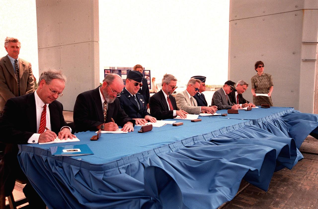 On the site of Launch Complex 34, key participants sign a Memorandum of Agreement, formalizing cooperative efforts of NASA, the U.S. Air Force, and federal agencies in ground-water cleanup initiatives. Seated from left to right are Timothy Oppelt, director, National Risk Management Research Laboratory, U.S. Environmental Protection Agency; Tom Heenan, assistant manager of environmental management, Savannah River Site, U.S. Department of Energy; Col. James Heald, Vice Commander, Air Force Research Laboratory, U.S. Air Force; Gerald Boyd, acting deputy assistant secretary, Office of Science and Technology, U.S. Department of Energy; James Fiore, acting deputy assistant secretary, Office of Environmental Restoration, Department of Energy; Brig. Gen. Randall R. Starbuck, Commander 45th Space Wing, U.S. Air Force; Roy Bridges Jr., director of John F. Kennedy Space Center; Walter Kovalick Jr., Ph.D., director, Technology Innovation Office, U.S. Environmental Protection Agency. NASA, the U.S. Air Force and the agencies have formed a consortium and are participating in a comparative study of three innovative techniques to be used in cleaning a contaminated area of Launch Complex 34. The study will be used to help improve groundwater cleanup processes nationally