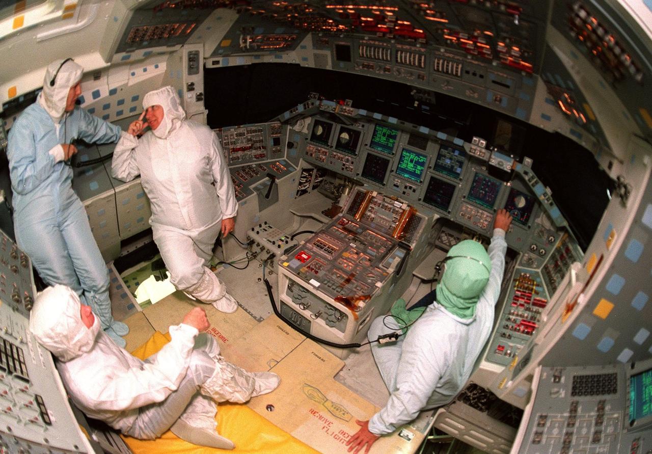 KENNEDY SPACE CENTER, FLA. -- Inside the orbiter Atlantis, Center Director Roy Bridges (seated at bottom left) and Associate Director for Advanced Development and Shuttle Upgrades JoAnn Morgan (standing second from left) learn about the new Multifunction Electronic Display Subsystem (MEDS) from Laural Patrick (standing left), a systems engineer with MEDS, and George Selina (at right), with United Space Alliance. Also called the "glass cockpit," the new full-color flat panel MEDS upgrade improves crew/orbiter interaction with easy-to-read, graphic portrayals of key flight indicators like attitude display and mach speed. The installation makes Atlantis the most modern orbiter in the fleet and equals the systems on current commercial jet airliners and military aircraft. Atlantis is scheduled to fly on mission STS-101 in early December