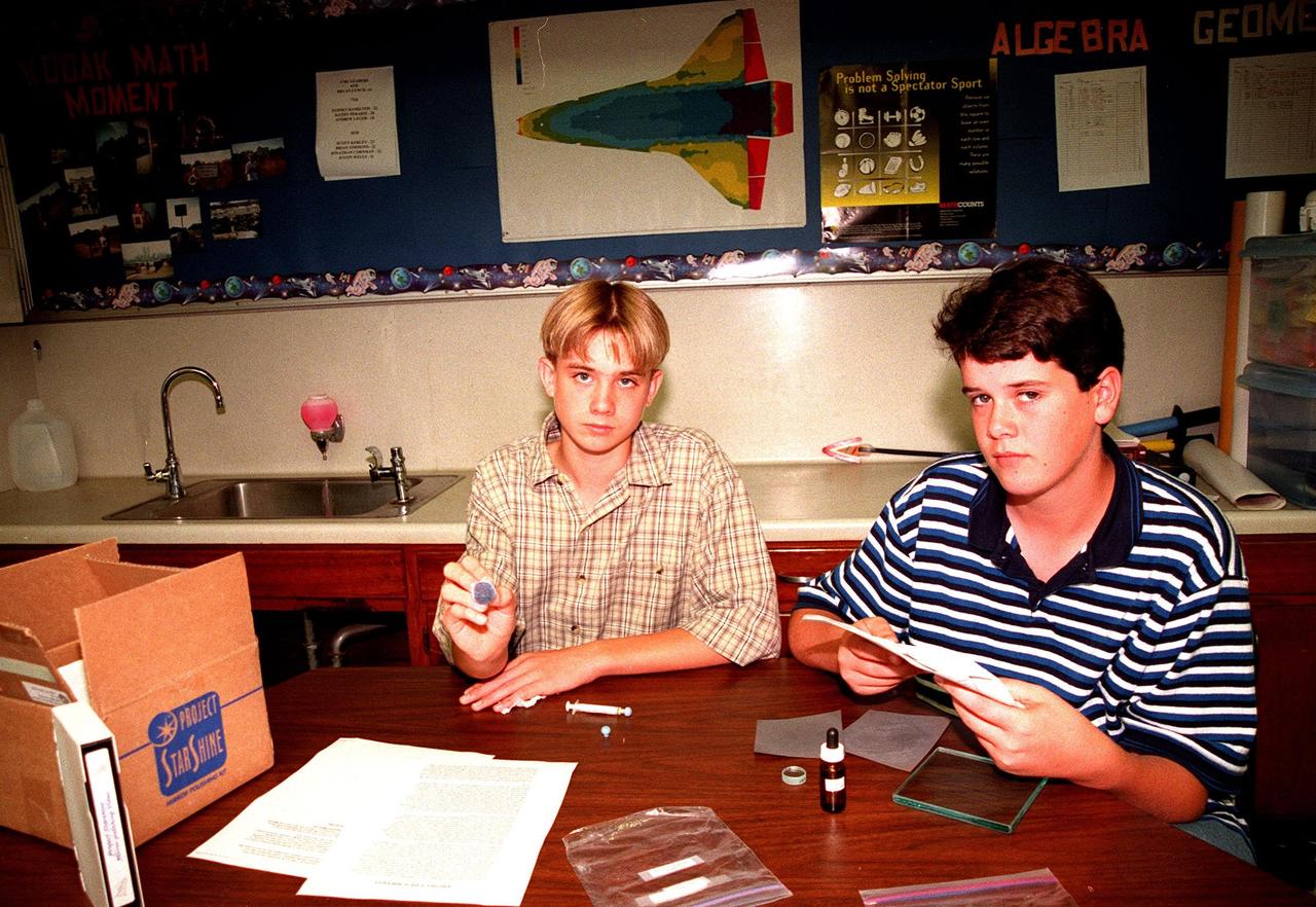 Students Scott Kerley and Bryan Geer demonstrate how they polished mirrors for STARSHINE, a student spacecraft built by the Naval Research Laboratory in Washington, D.C. The two seventh graders at McNair Magnet School, Cocoa Beach, Fla., are among dozens of students teams of elementary, middle and high school students who have polished nearly nine hundred of the one-inch mirrors and returned them to Utah for coating with a protective transparent layer of Silicon Dioxide at Hill Air Force Base. The mirrors are being mounted on the surface of the spacecraft. STARSHINE is being deployed into a highly inclined low-earth orbit from a Hitchhiker canister on mission STS-96, targeted to launch May 20. After deployment from the Shuttle in May, the spacecraft will reflect flashes of sunlight to observers on the earth during the mission. This twinkling satellite will be naked-eye visible against the star background for about six months during recurring morning and evening twilight periods to student observers around the world