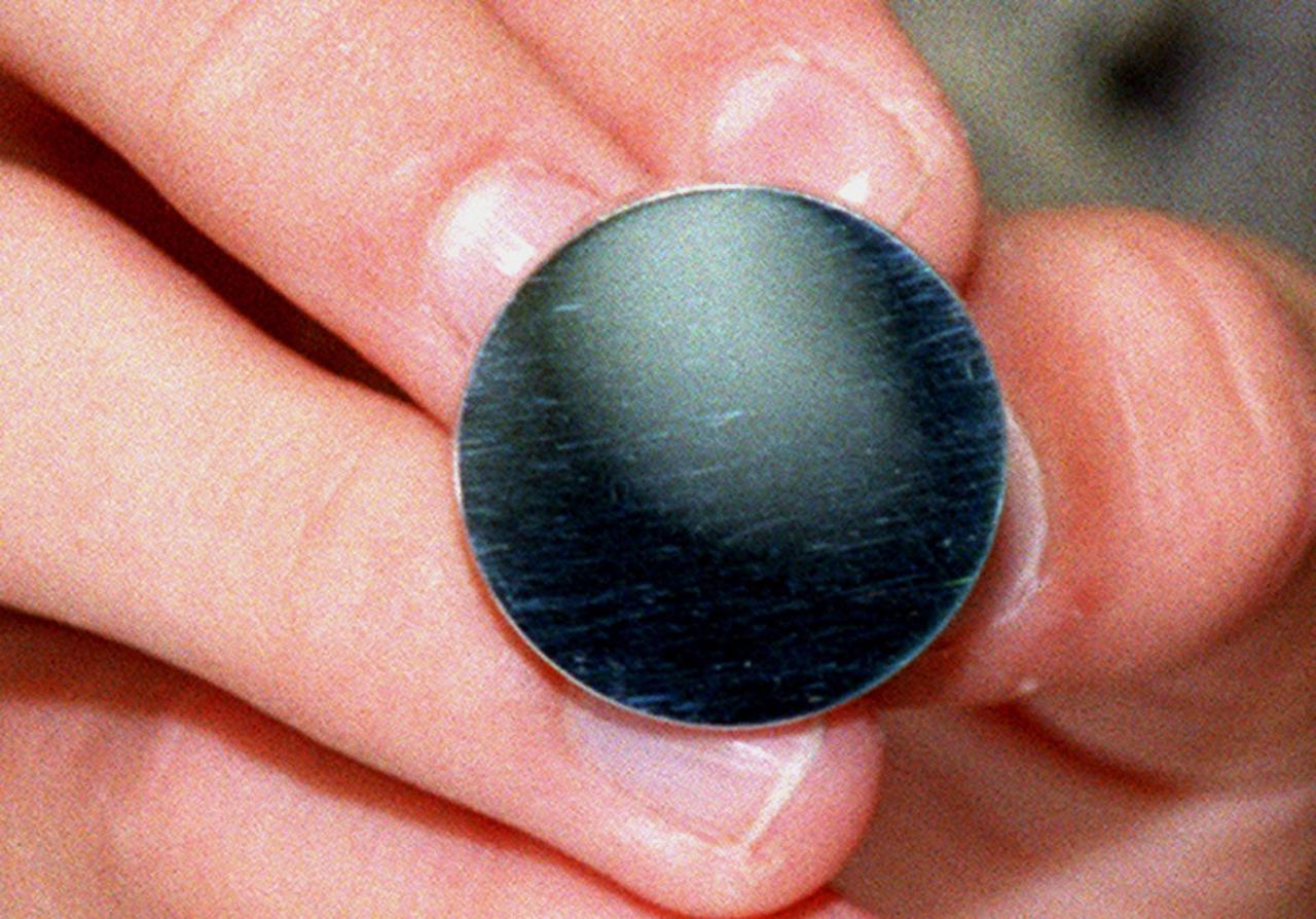 The one-inch mirror shown here is one of nearly nine hundred polished by dozens of students teams of elementary, middle and high school students across the nation as part of STARSHINE, a student spacecraft built by the Naval Research Laboratory in Washington, D.C. After being coated with a protective transparent layer of Silicon Dioxide at Hill Air Force Base, they are being mounted on the surface of the spacecraft. STARSHINE is being deployed into a highly inclined low-earth orbit from a Hitchhiker canister on mission STS-96, targeted to launch May 20. After deployment from the Shuttle in May, the spacecraft will reflect flashes of sunlight to observers on the earth during the mission. This twinkling satellite will be naked-eye visible against the star background for about six months during recurring morning and evening twilight periods to student observers around the world