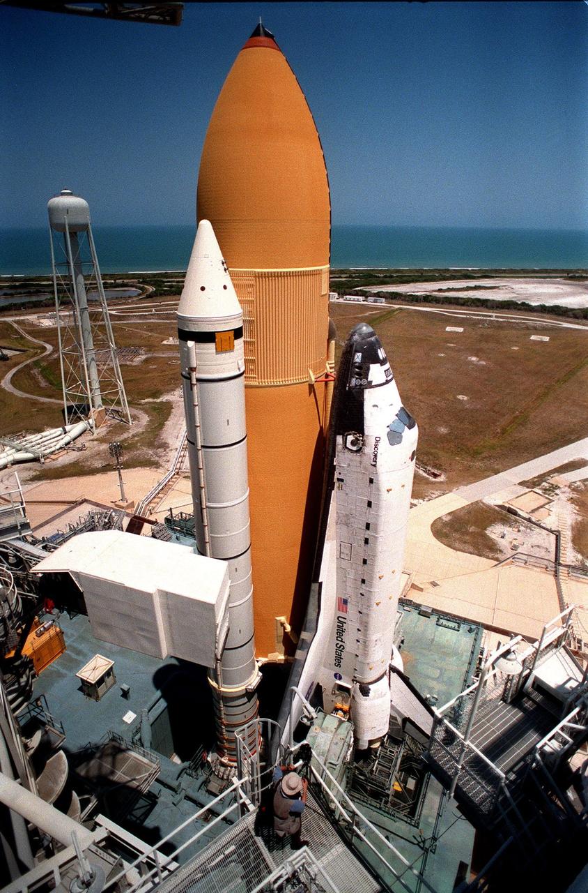 KENNEDY SPACE CENTER, FLA. -- Space Shuttle Discovery sits on Launch Pad 39B against a backdrop of blue sky and the blue-green Atlantic Ocean. At the top left is the 290-foot-high water tank that holds 300,000 gallons of water for the sound suppression system during liftoff. At the bottom, on the Rotating Service Structure, is photographer John Sexton, taking photos for a book. Liftoff of Discovery on mission STS-96 is targeted for May 20 at 9:32 a.m. EDT. STS-96 is a logistics and resupply mission for the International Space Station, carrying such payloads as a Russian crane, the Strela; a U.S.-built crane; the Spacehab Oceaneering Space System Box (SHOSS), a logistics items carrier; and STARSHINE, a student-led experiment