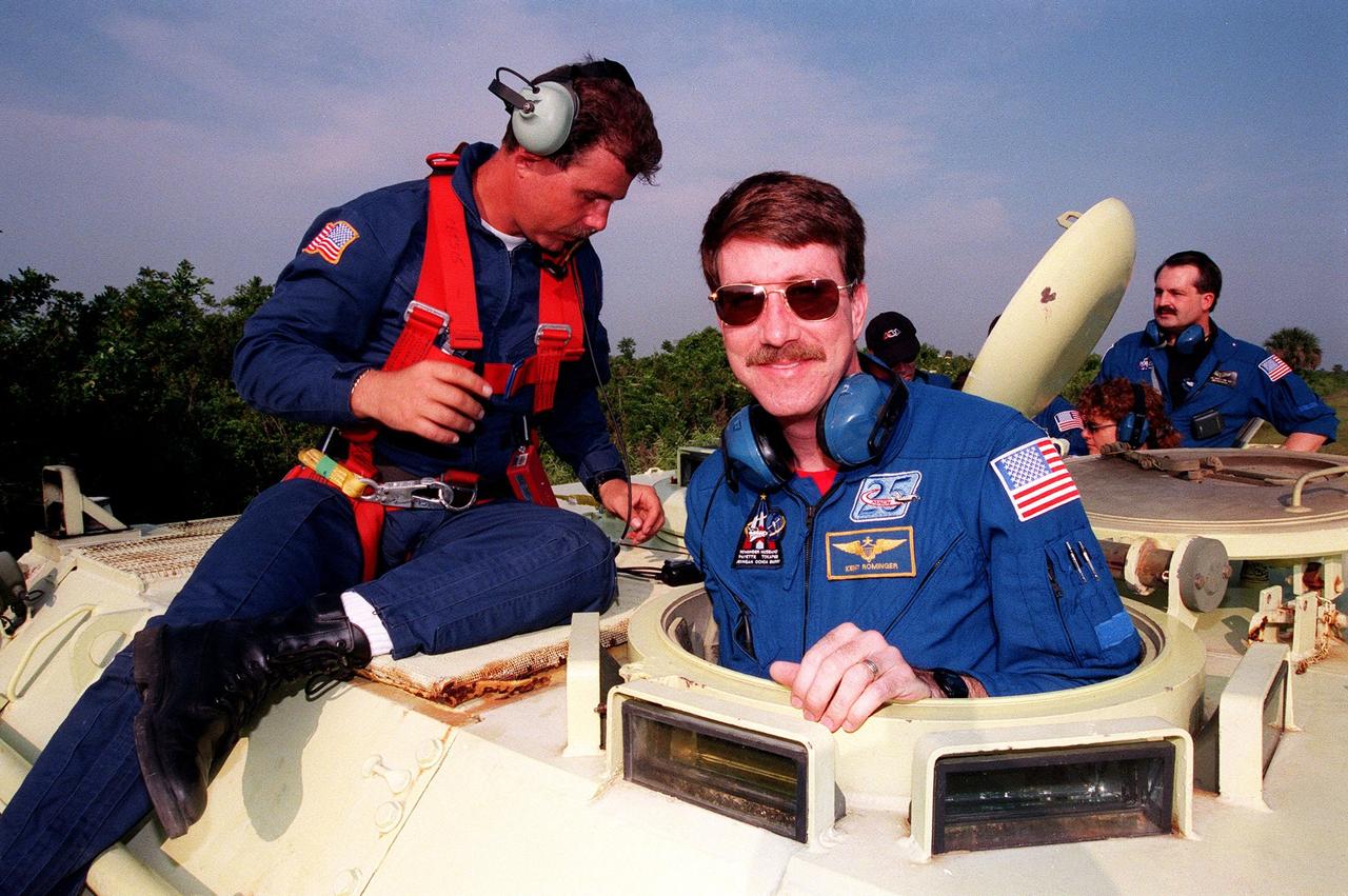 Under the eye of Capt. Steve Kelly (left), with Space Gateway Support, Commander Kent V. Rominger gets ready to practice driving the small armored personnel carrier that is part of emergency egress training during Terminal Countdown Demonstration Test (TCDT) activities. At the rear is Douglas Hamilton, a Canadian flight surgeon. The tracked vehicle could be used by the crew in the event of an emergency at the pad during which the crew must make a quick exit from the area. The TCDT also provides simulated countdown exercises and opportunities to inspect the mission payloads in the orbiter's payload bay. Other crew members taking part in the TCDT are Pilot Rick Douglas Husband, and Mission Specialists Ellen Ochoa (Ph.D.), Tamara E. Jernigan (Ph.D.), Daniel Barry (M.D., Ph.D.), Julie Payette and Valery Ivanovich Tokarev. Payette represents the Canadian Space Agency and Tokarev the Russian Space Agency. Mission STS-96, which is scheduled for liftoff on May 20 at 9:32 a.m., is a logistics and resupply mission for the International Space Station, carrying such payloads as a Russian crane, the Strela; a U.S.-built crane; the Spacehab Oceaneering Space System Box (SHOSS), a logistics items carrier; and STARSHINE, a student-led experiment