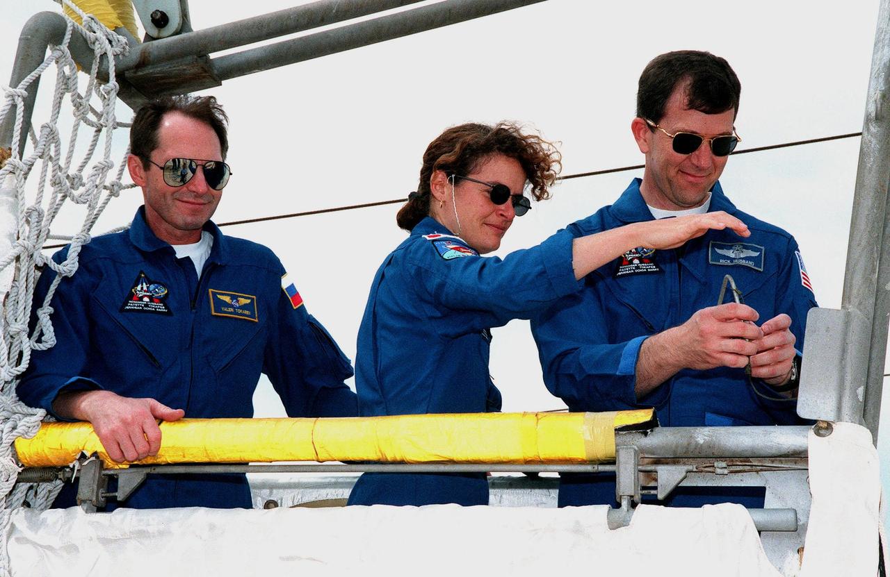 At the 195-foot level of Launch Pad 39B, STS-96 Mission Specialists Valery Ivanovich Tokarev and Julie Payette, plus Pilot Rick Douglas Husband, inspect the slidewire basket used for emergency egress. The training is part of Terminal Countdown Demonstration Test (TCDT) activities, which also provide the crew with simulated countdown exercises and opportunities to inspect the mission payloads in the orbiter's payload bay. Other crew members taking part in the TCDT are Commander Kent V. Rominger and Mission Specialists Tamara E. Jernigan (Ph.D.), Daniel Barry (M.D., Ph.D.), and Ellen Ochoa (Ph.D.). Scheduled for liftoff on May 20 at 9:32 a.m., STS-96 is a logistics and resupply mission for the International Space Station, carrying such payloads as a Russian crane, the Strela; a U.S.-built crane; the Spacehab Oceaneering Space System Box (SHOSS), a logistics items carrier; and STARSHINE, a student-led experiment