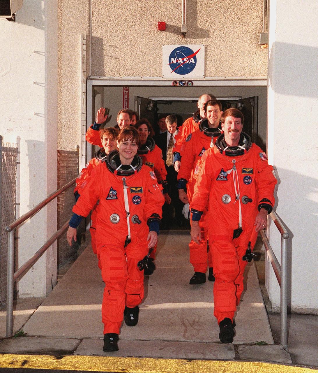 The STS-96 crew exit the Operations and Checkout Building after suiting up for their practice countdown exercise as part of Terminal Countdown Demonstration Test (TCDT) activities. The TCDT also provides the crew with emergency egress training and opportunities to inspect the mission payloads in the orbiter's payload bay. Clockwise starting from the front left are Mission Specialists Tamara E. Jernigan (Ph.D.), Julie Payette, Ellen Ochoa (Ph.D.), Valery Ivanovich Tokarev; (right side) Daniel Barry (M.D., Ph.D.), Pilot Rick Douglas Husband, and Commander Kent V. Rominger. Scheduled for liftoff on May 20 at 9:32 a.m., STS-96 is a logistics and resupply mission for the International Space Station, carrying such payloads as a Russian crane, the Strela; a U.S.-built crane; the Spacehab Oceaneering Space System Box (SHOSS), a logistics items carrier; and STARSHINE, a student-led experiment