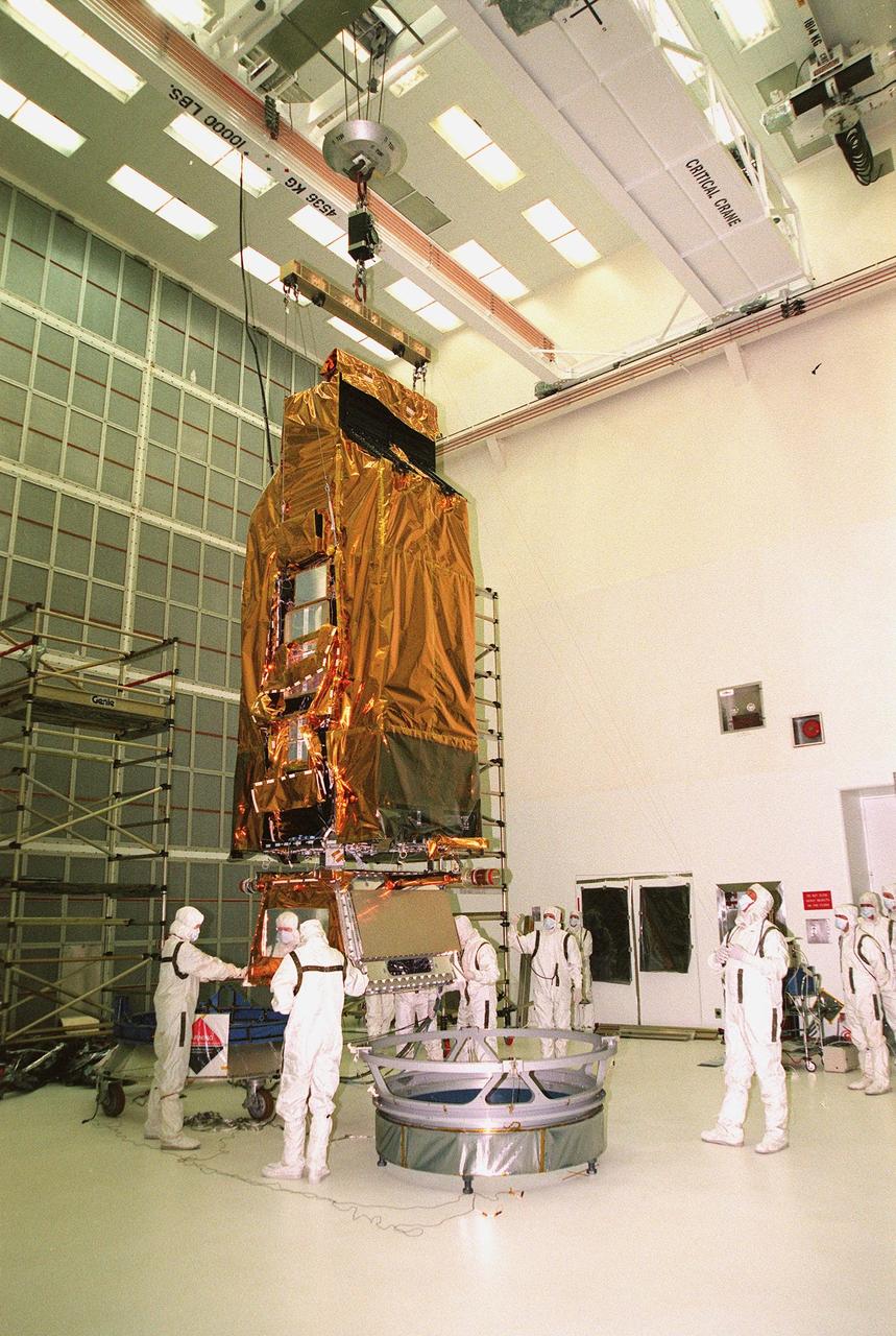 While a crane lifts NASA's Far Ultraviolet Spectroscopic Explorer (FUSE) satellite, workers at Hangar AE, Cape Canaveral Air Station, help guide it toward the circular Payload Attach Fitting (PAF) in front of it. FUSE is undergoing a functional test of its systems, plus installation of flight batteries and solar arrays. Developed by The Johns Hopkins University under contract to Goddard Space Flight Center, Greenbelt, Md., FUSE will investigate the origin and evolution of the lightest elements in the universe hydrogen and deuterium. In addition, the FUSE satellite will examine the forces and process involved in the evolution of the galaxies, stars and planetary systems by investigating light in the far ultraviolet portion of the electromagnetic spectrum. FUSE is scheduled to be launched May 27 aboard a Boeing Delta II rocket at Launch Complex 17
