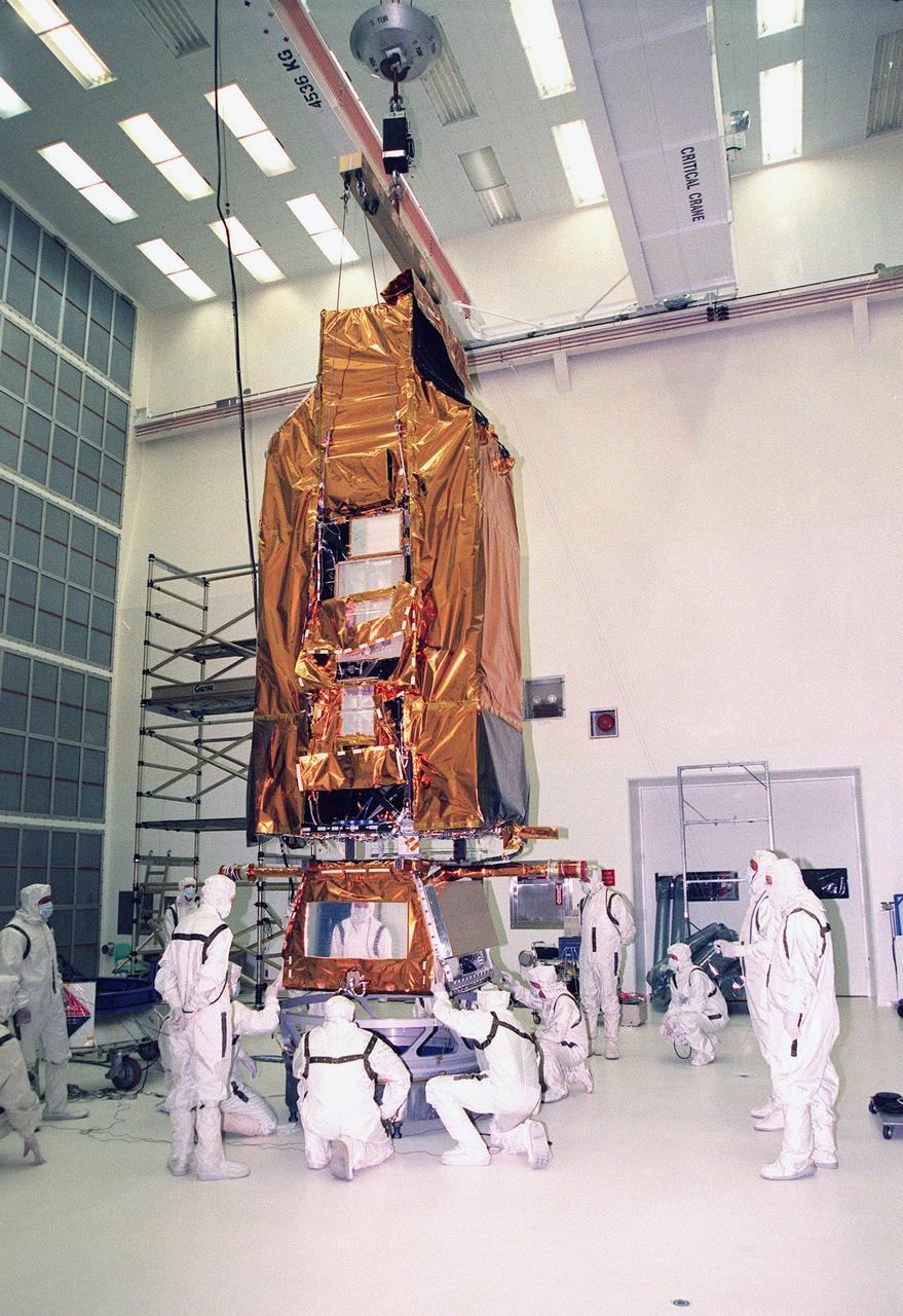 Suspended by a crane in Hangar AE, Cape Canaveral Air Station, NASA's Far Ultraviolet Spectroscopic Explorer (FUSE) satellite is lowered onto a circular Payload Attach Fitting (PAF). FUSE is undergoing a functional test of its systems, plus installation of flight batteries and solar arrays. Developed by The Johns Hopkins University under contract to Goddard Space Flight Center, Greenbelt, Md., FUSE will investigate the origin and evolution of the lightest elements in the universe hydrogen and deuterium. In addition, the FUSE satellite will examine the forces and process involved in the evolution of the galaxies, stars and planetary systems by investigating light in the far ultraviolet portion of the electromagnetic spectrum. FUSE is scheduled to be launched May 27 aboard a Boeing Delta II rocket at Launch Complex 17