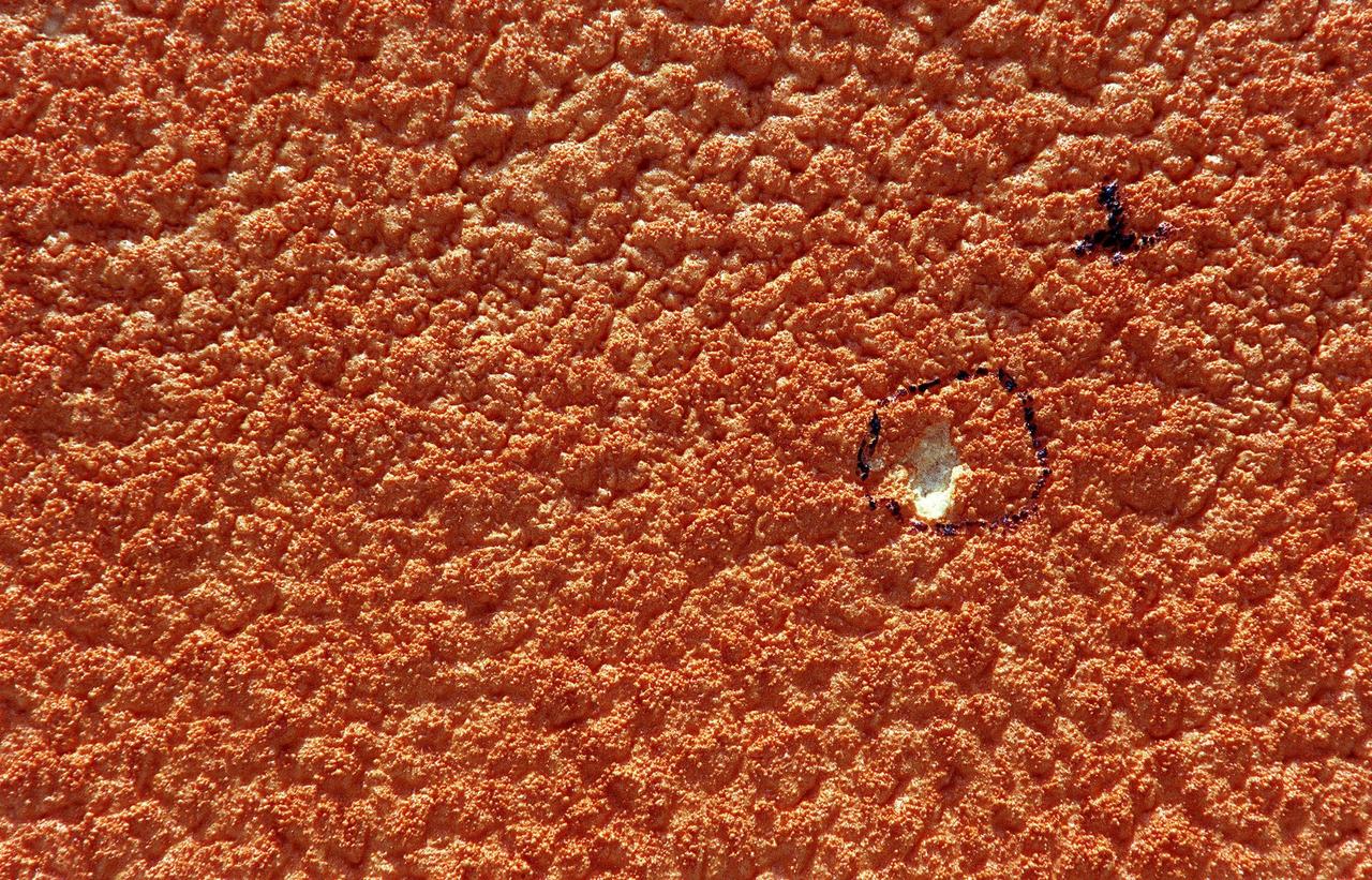 A hole, created by recent hail storms, is identified as number one on the surface of the external tank (ET) mated to Space Shuttle Discovery at Launch Pad 39B. Workers are investigating the damage and potential problems for launch posed by ice forming in the holes, which may number as many as 150 over the entire tank. The average size of the holes is one-half inch in diameter and one-tenth inch deep. The external tank contains the liquid hydrogen fuel and liquid oxygen oxidizer and supplies them under pressure to the three space shuttle main engines in the orbiter during liftoff and ascent. The ET thermal protection system consists of sprayed-on foam insulation. The Shuttle Discovery is targeted for launch of mission STS-96 on May 20 at 9:32 a.m