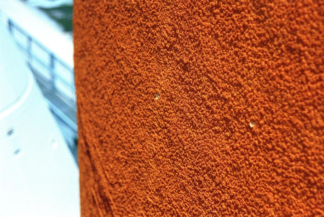 At Launch Pad 39B, two holes caused by hail on Space Shuttle Discovery's external tank (ET) are visible. Left of the tank is one of the solid rocket boosters. Workers are investigating the damage and potential problems for launch posed by ice forming in the holes, which may number as many as 150 over the entire tank. The average size of the holes is one-half inch in diameter and one-tenth inch deep. The external tank contains the liquid hydrogen fuel and liquid oxygen oxidizer and supplies them under pressure to the three space shuttle main engines in the orbiter during liftoff and ascent. The ET thermal protection system consists of sprayed-on foam insulation. The Shuttle Discovery is targeted for launch of mission STS-96 on May 20 at 9:32 a.m