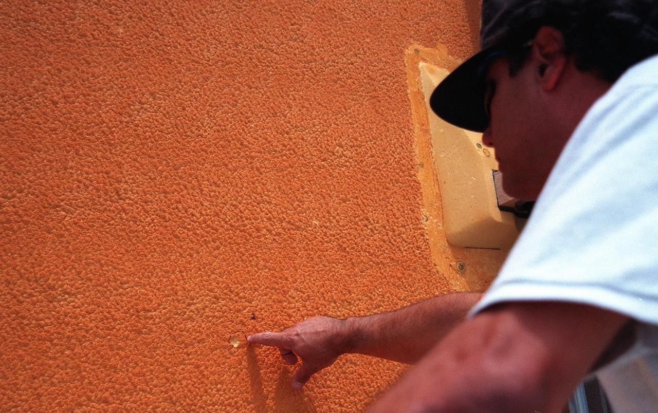 At Launch pad 39B, Mike Barber, with United Space Alliance safety, points to one of the holes caused by hail on Space Shuttle Discovery's external tank (ET). Workers are investigating the damage and potential problems for launch posed by ice forming in the holes, which may number as many as 150 over the entire tank. The average size of the holes is one-half inch in diameter and one-tenth inch deep. The external tank contains the liquid hydrogen fuel and liquid oxygen oxidizer and supplies them under pressure to the three space shuttle main engines in the orbiter during liftoff and ascent. The ET thermal protection system consists of sprayed-on foam insulation. The Shuttle Discovery is targeted for launch of mission STS-96 on May 20 at 9:32 a.m